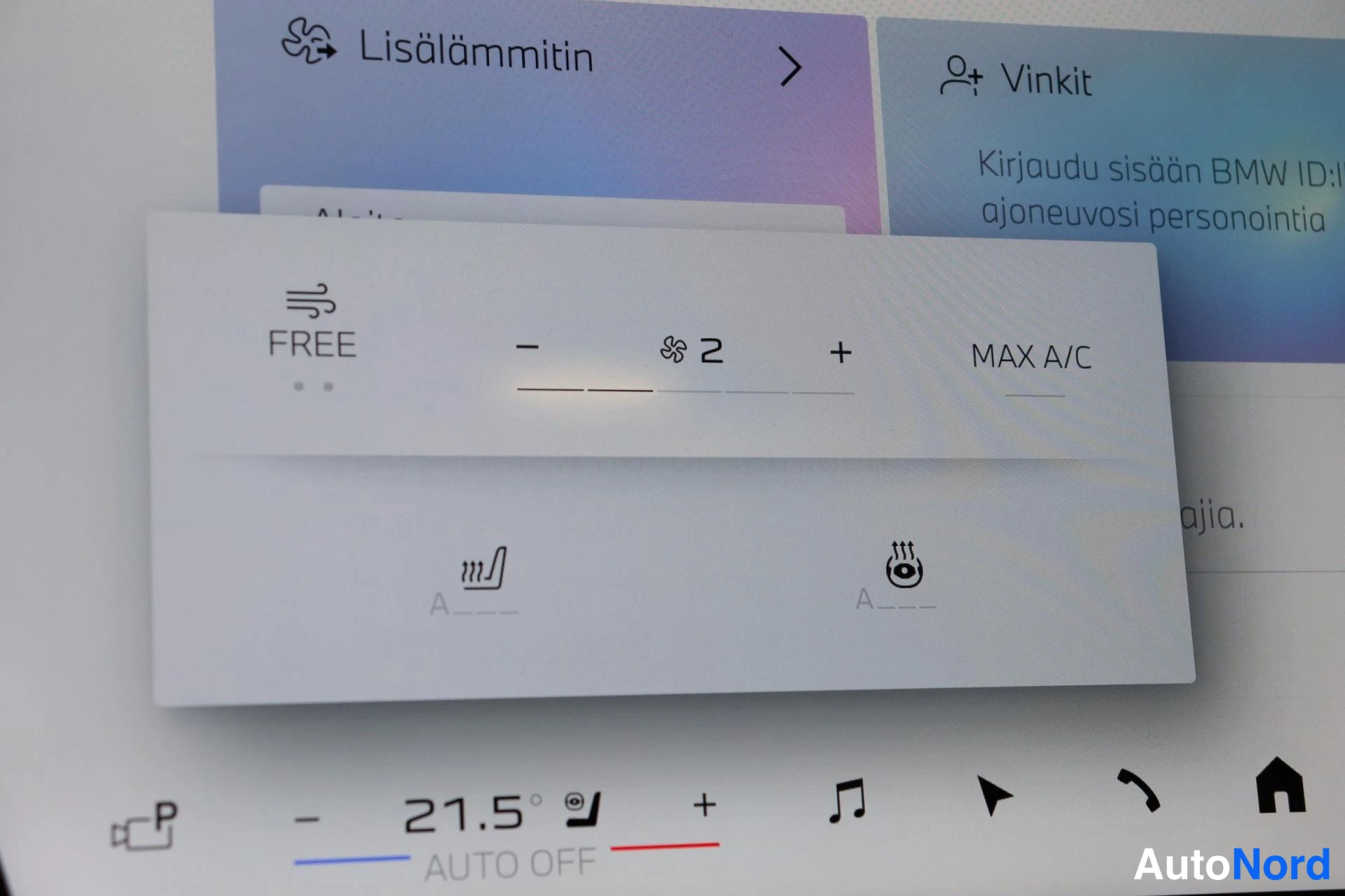 Ohjaamo: Lähikuva ilmastointiohjaimista keskusnäytössä: 'FREE' -ikkuna, tuulettimen pyöritysaste '2', painikkeet '-', '+' sekä teksti 'MAX A/C'. Näytössä näkyvät ikonit