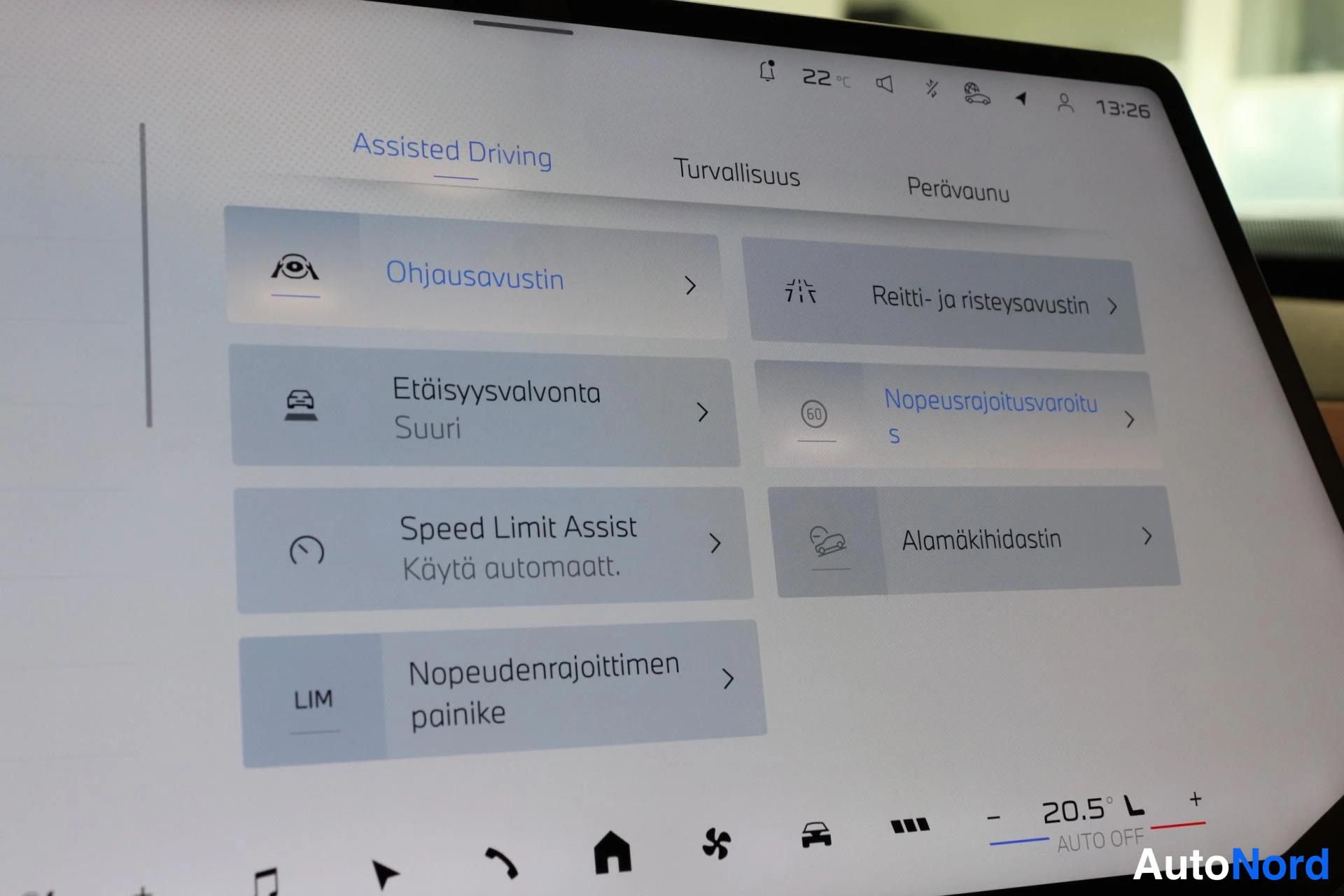 Ohjaamo: Tukiohjauksien (Assisted Driving) valikko keskellä kosketusnäyttöä. Vasemmassa sarakkeessa rivit: 'Ohjausavustin' (steering assist), 'Etäisyysvalvonta Suuri' (d
