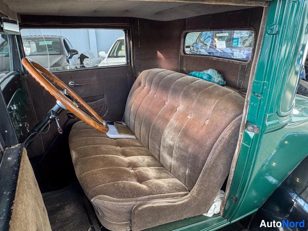 Ohjaamo: Interior view focused on the long, brown upholstered bench seat. A light blue object rests on the rear portion of the seat.