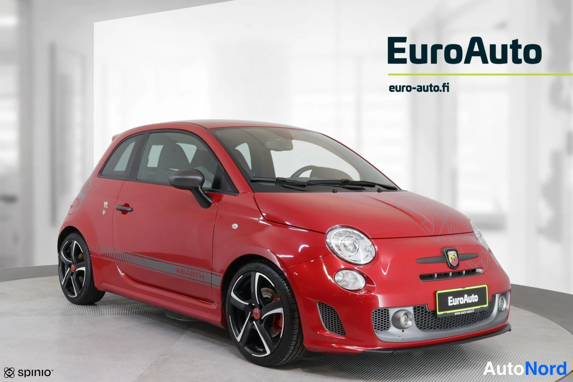 Etuviisto, nokka vasemmalle: Red Fiat Abarth 595 viewed from the front-left. The image shows the front grille, headlights, and left side of the car including the black alloy wheels