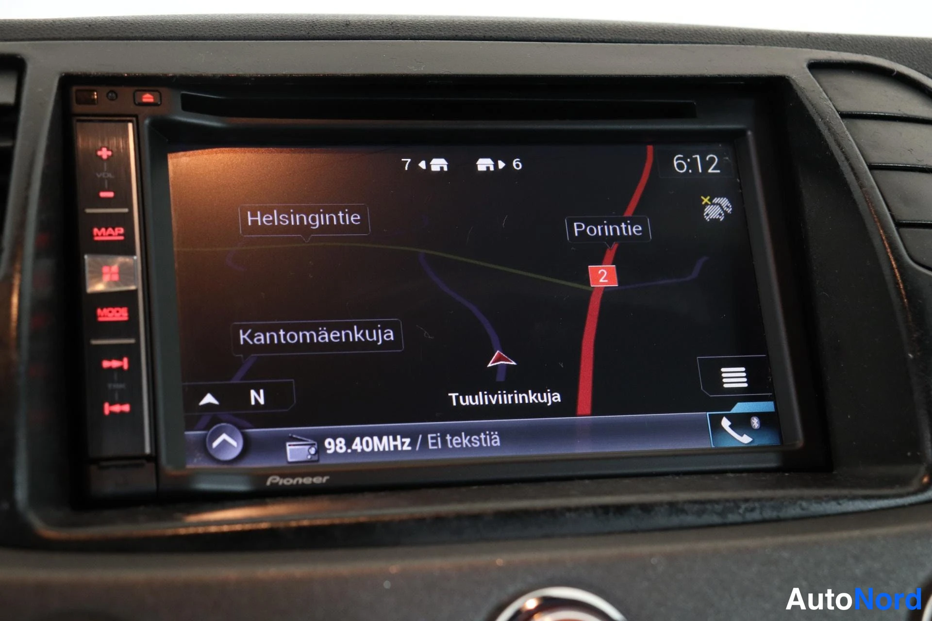 Muu: Auton kojelaudassa Pioneer-navigointiradio, jonka näytöllä on kartta kadunnimillä Helsingintie, Porintie, Kantomäenkuja ja Tuuliviirinkuja sekä radiotaajuus 98.