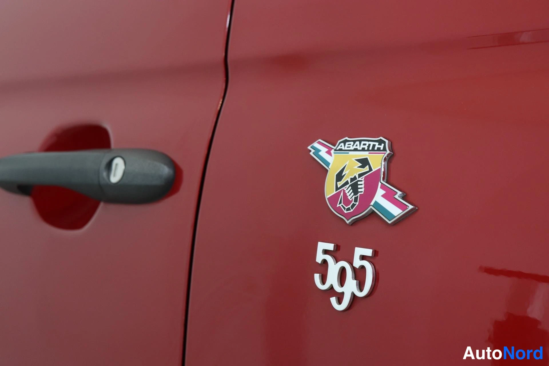 Yksityiskohta: Ovenkahvan vieressä oleva ABARTH-ruusuke ja '595'-kirjoitus punaisessa karossissa.