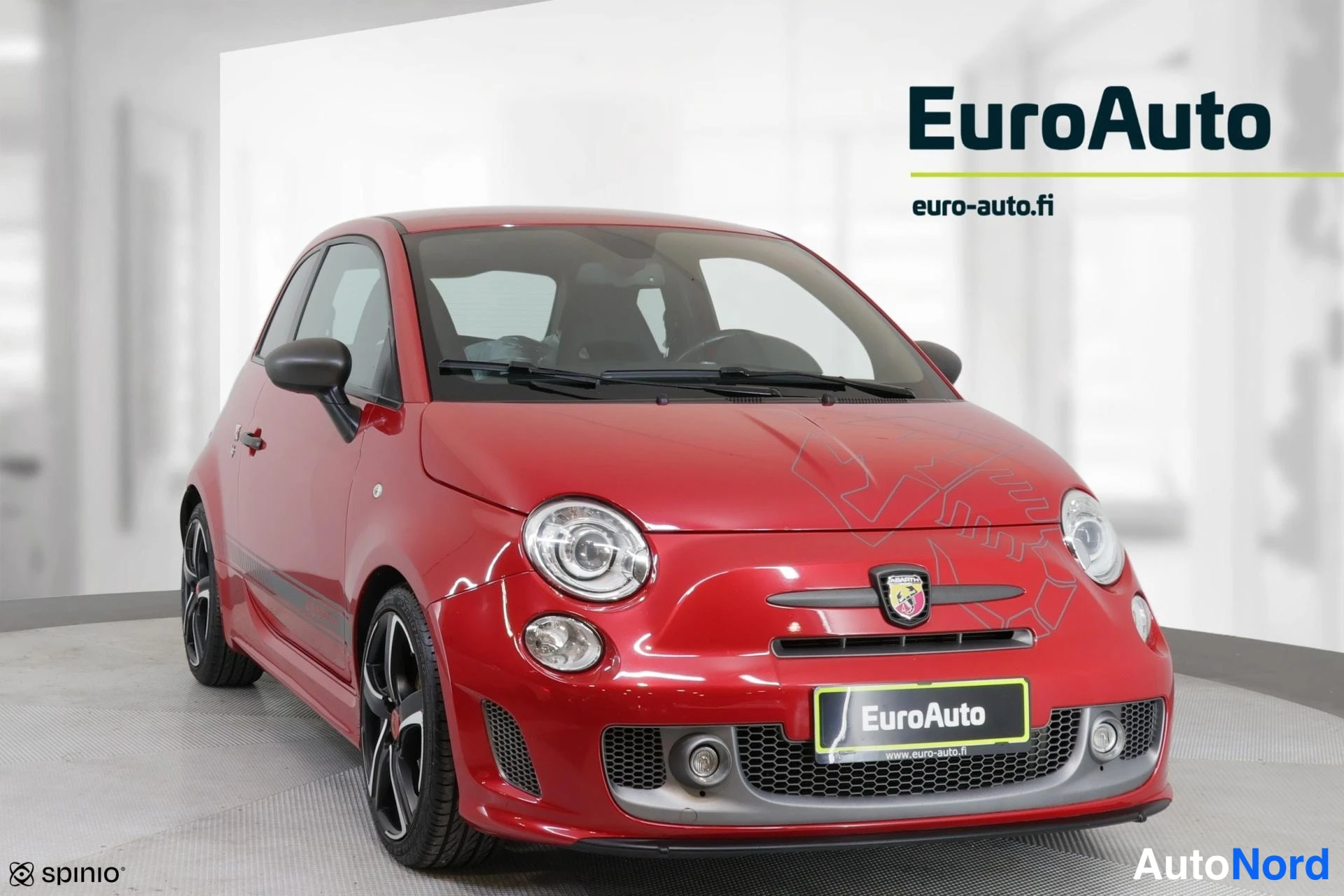 Etuviisto, nokka oikealle: Red Fiat Abarth 595 three-quarter front view in a studio setting. The car's front grille with the Abarth scorpion logo is visible along with the left hea