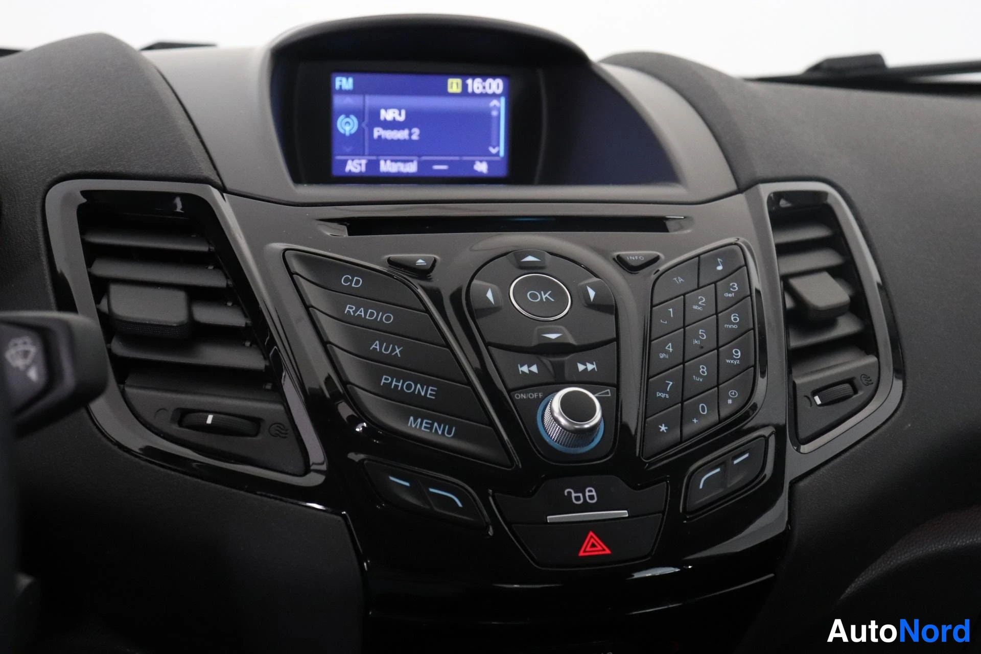 Ohjaamo: Dashboard interior view showing a central infotainment display with FM radio interface and climate control settings, flanked by air vents and buttons for CD, RA