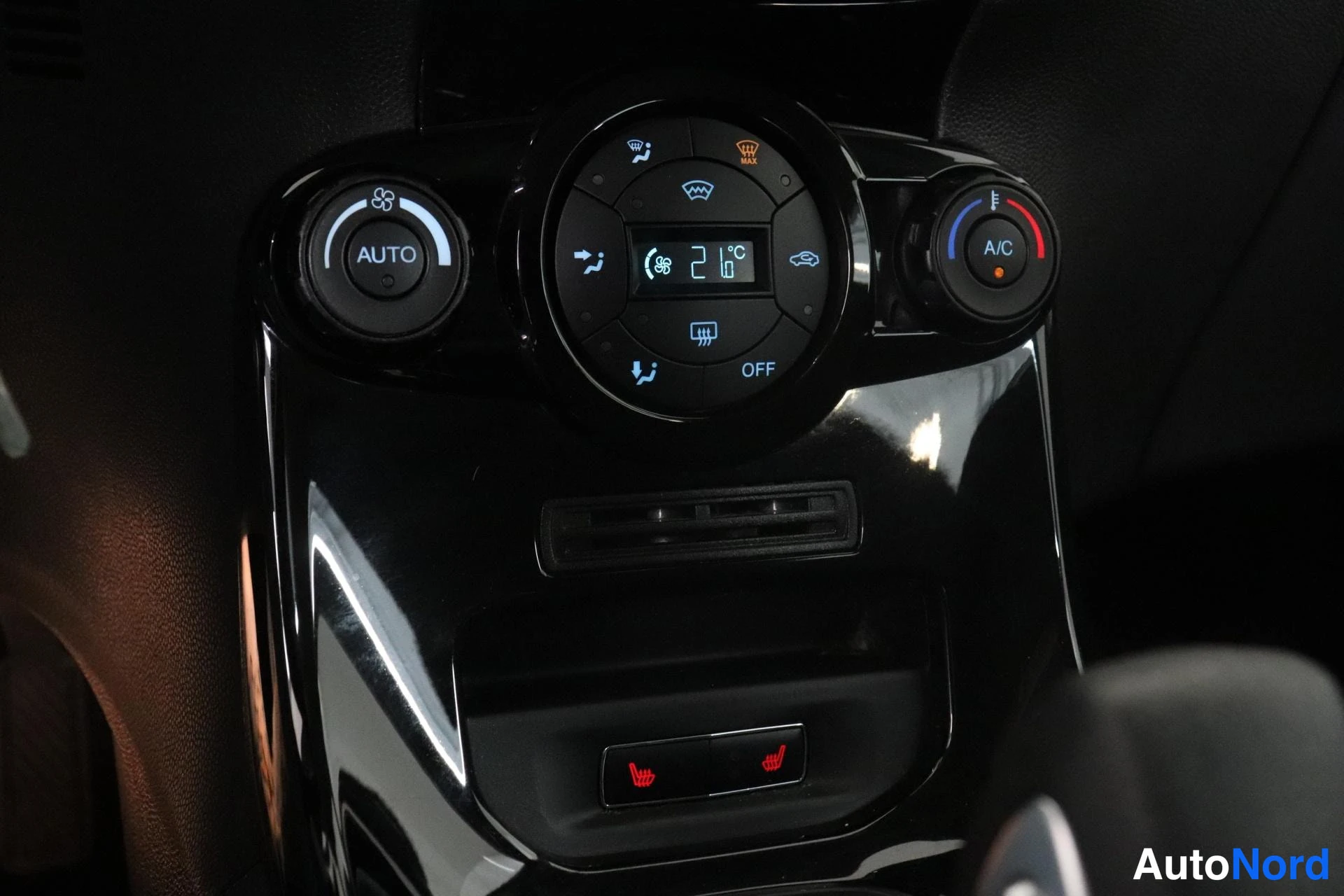 Ohjaamo: Close-up of dual-zone automatic climate control panel with digital temperature display reading 21°C. Controls include AUTO mode, A/C toggle, fan speed, defrost