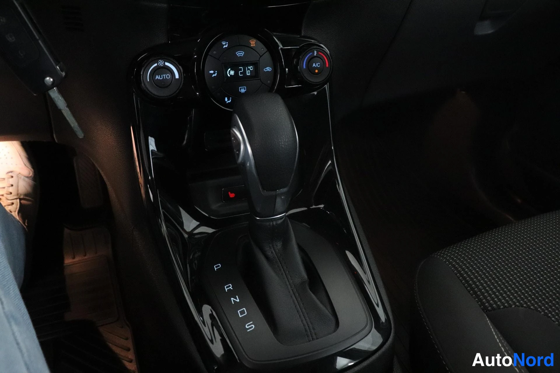 Ohjaamo: Automatic transmission gear selector lever in black leather boot, positioned in center console. Gear positions P R N D S are clearly labeled on the console surf