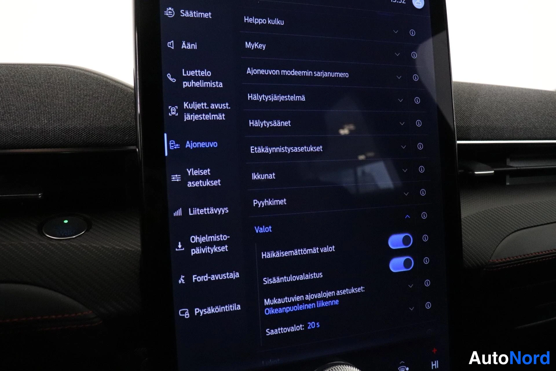 Muu: Auton infotainment-näyttö, jossa on avoinna suomenkielinen Ajoneuvo-asetusvalikko (mm. Hälytysjärjestelmä, Ikkunat ja Valot).