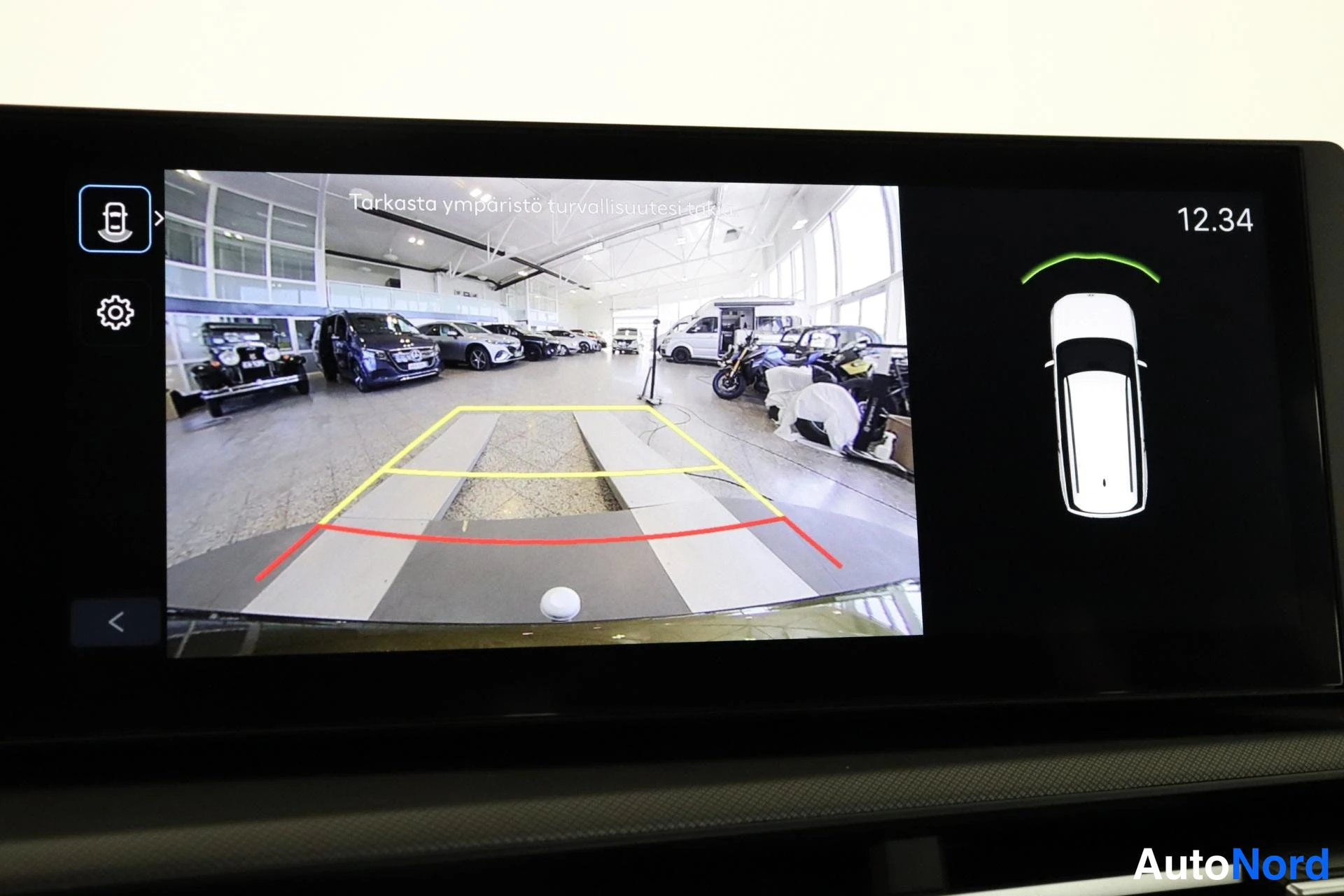 Muu: Infotainment-näytön 360-kameranäkymä showroomista: keltaiset ja punaiset parkointiviivat, varoitusteksti 'Tarkasta ympäristö turvallisuutesi', auton yläkuvake v