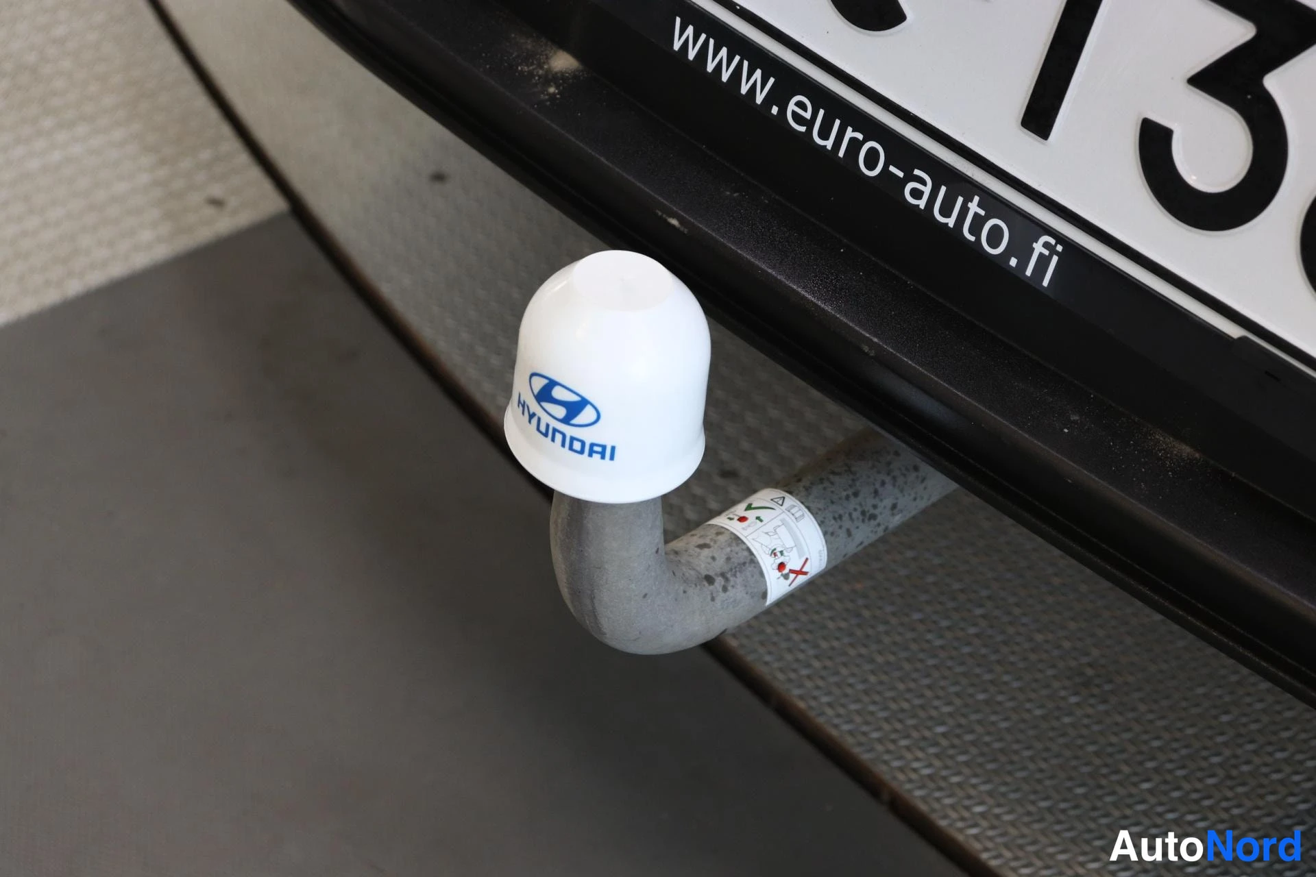 Muu: Hinauskytkimen kaula takapuskurin alla; sähköpistorasian suojana valkoinen korkki, jossa sininen Hyundai-merkintä ja teksti HYUNDAI. Rekisterikilven alareunassa