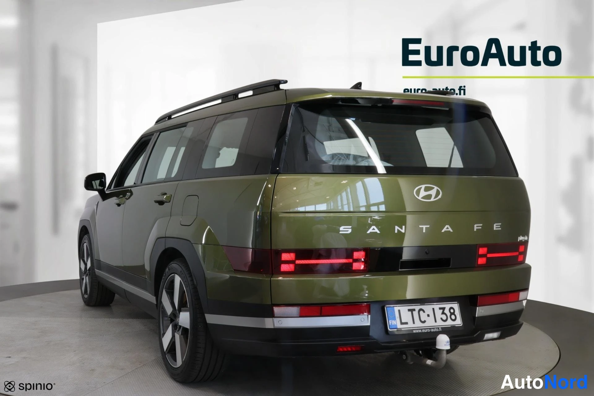 Takaviisto: Hyundai Santa Fe takaviistosta kuvattuna: oliivinvihreä kori, kattokaiteet, H-muotoiset takavalot, takaluukun SANTA FE -teksti ja rekisteri.