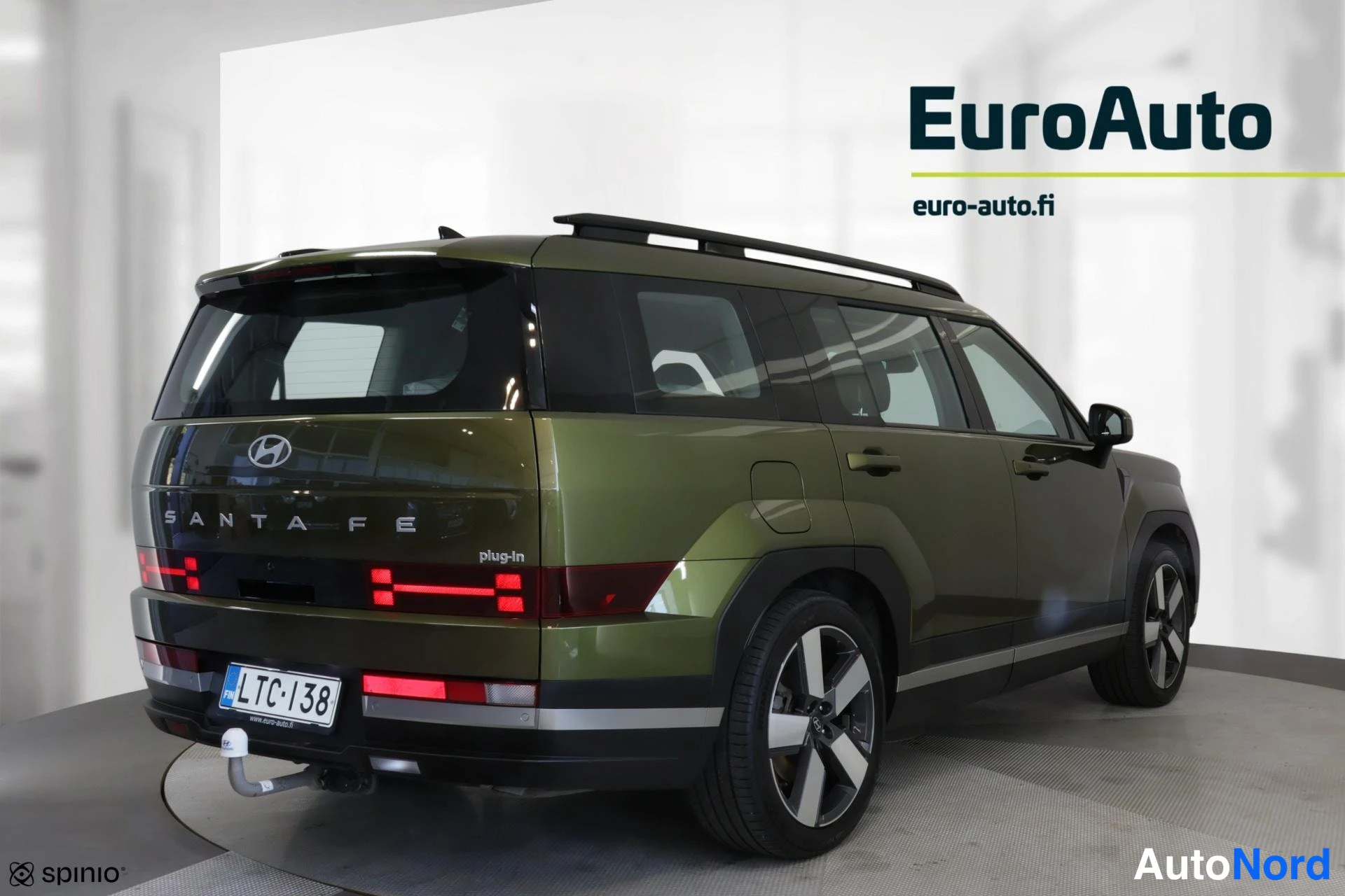 Takaviisto: Repu kolme neljäs: vihreä Hyundai Santa Fe Plug-In, jossa on kattoharjat ja vetokoukku.