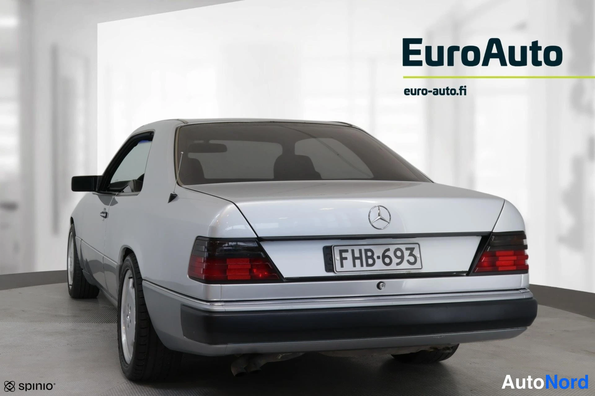 Takaviisto: Takakulmasta kuvattu hopeanvärinen Mercedes-Benz-coupé studiotakeessa; auton perä ja vasen kylki näkyvät, takaluukussa Mercedes-tähti ja rekisterikilpi.