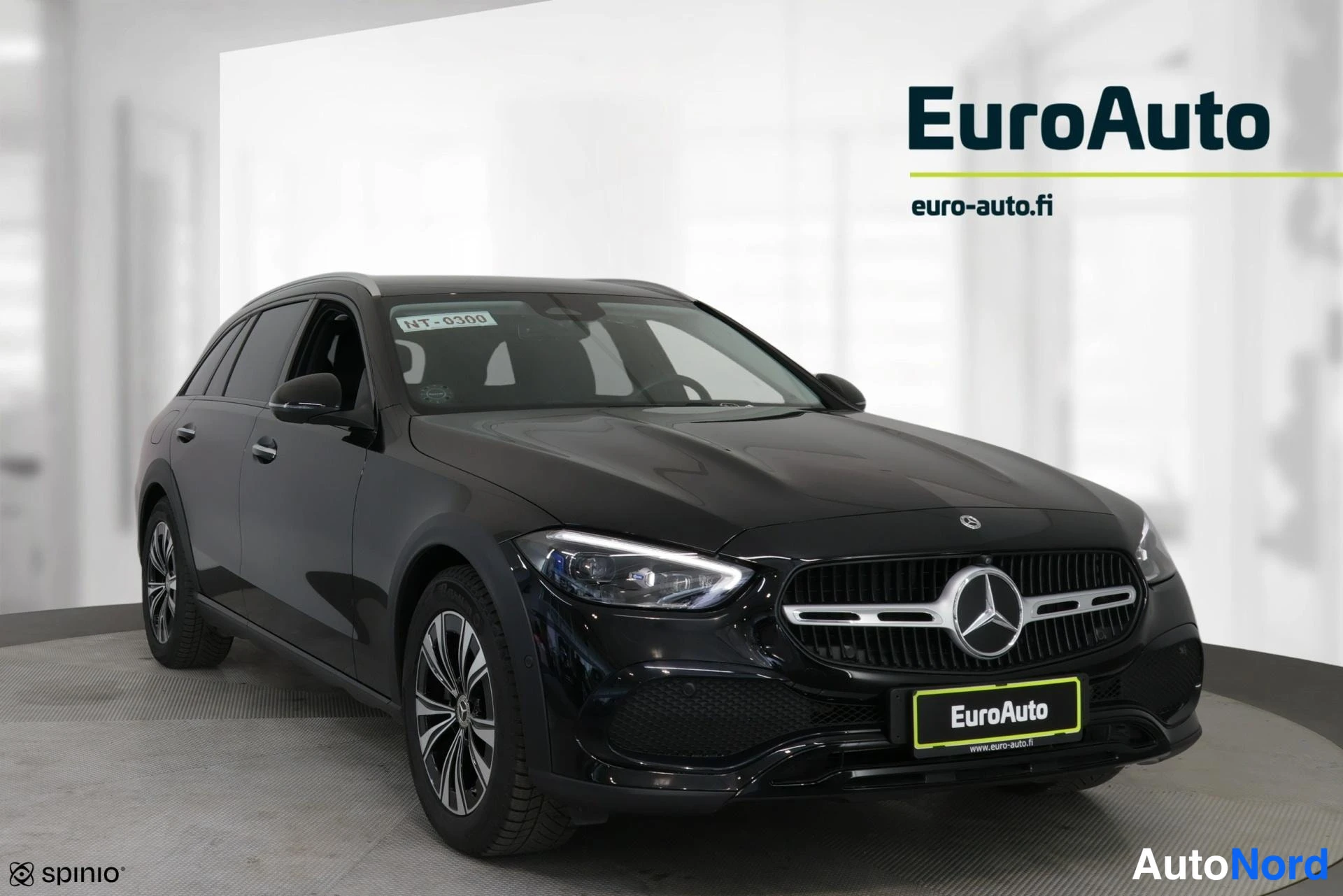 Etuviisto, nokka oikealle: Musta Mercedes-Benz-farmari kuvattuna etukulmasta, keula kuvan oikealla laidalla; kylki, kattokaiteet ja kevytmetallivanteet näkyvät studiovalaistuksessa