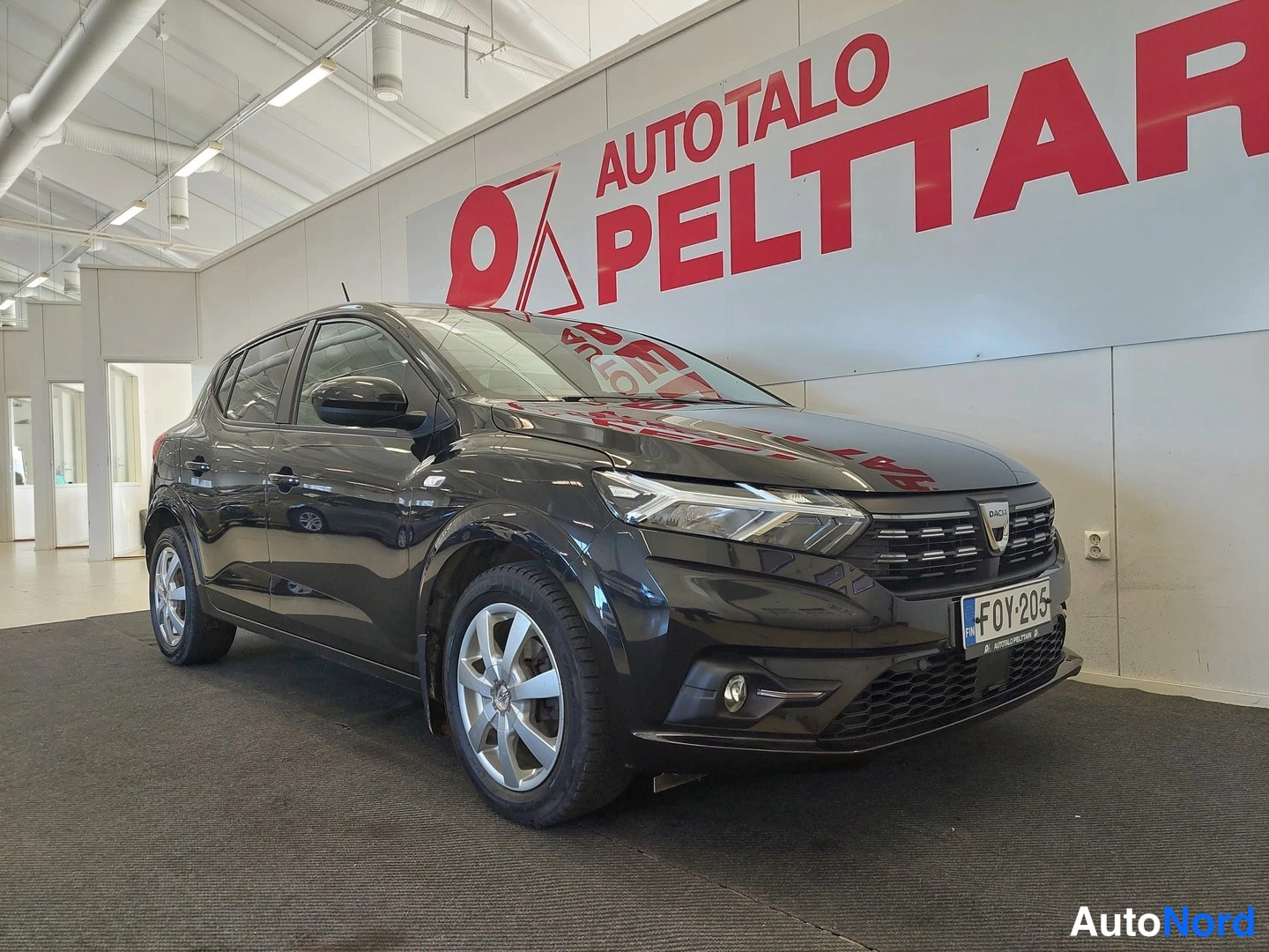 Etuviisto, nokka oikealle: Mustan hatchbackin etukulma vasemmalta sisätiloissa.
