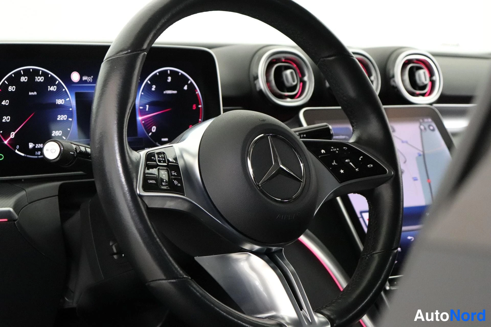 Etuistuimet: Ohjauspultti Mercedes-Benz -logolla ja digitaaliset mittarit ruudulla