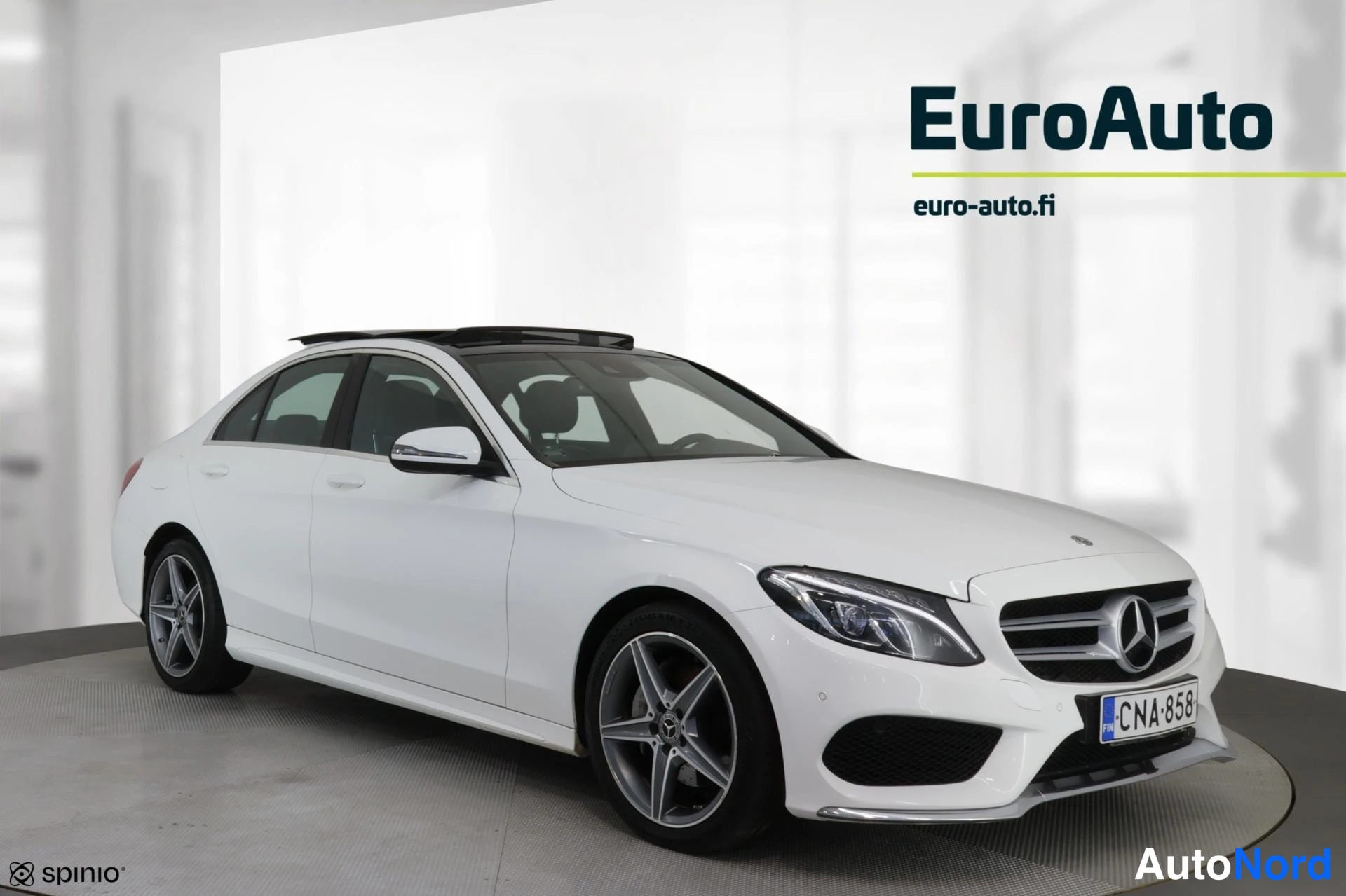 Etuviisto, nokka oikealle: Valkoinen Mercedes-Benz-sedan etuviistosta, keula kuvan oikeassa laidassa; lasikatto, kevytmetallivelimet ja rekisterikilpi näkyvissä.