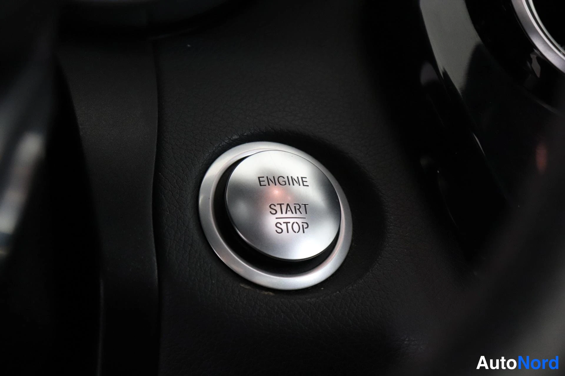 Edestä: Moottorin käynnistyspainike harmaalla kilpi ilman lainsäädäntöä on lautasella ENGINE START STOP.