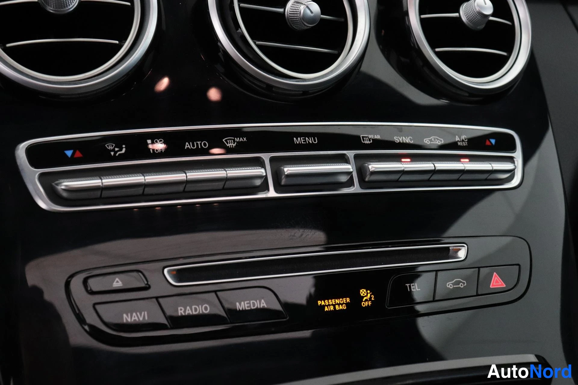 Edestä: Radio- ja navigointipainikkeet MINI-appi-kuvaan, jota asenne on suojattu napoilla NAVI RADIO MEDIA ja ilmastointiautomaatti AUTO A/C, SYNC.