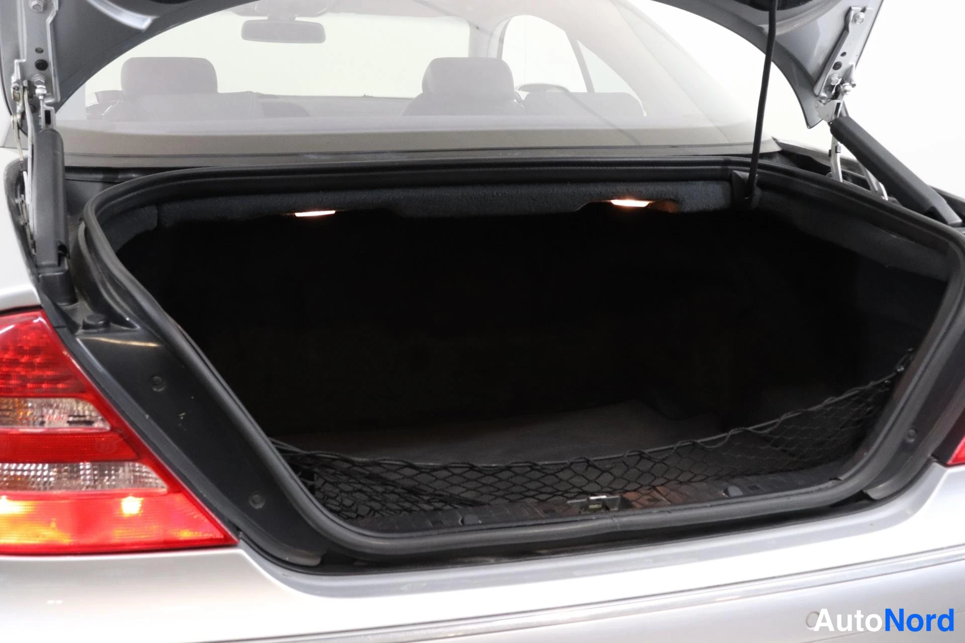 Takaa: Open trunk with bootlid raised, dark cargo mat and cargo net lining the floor.