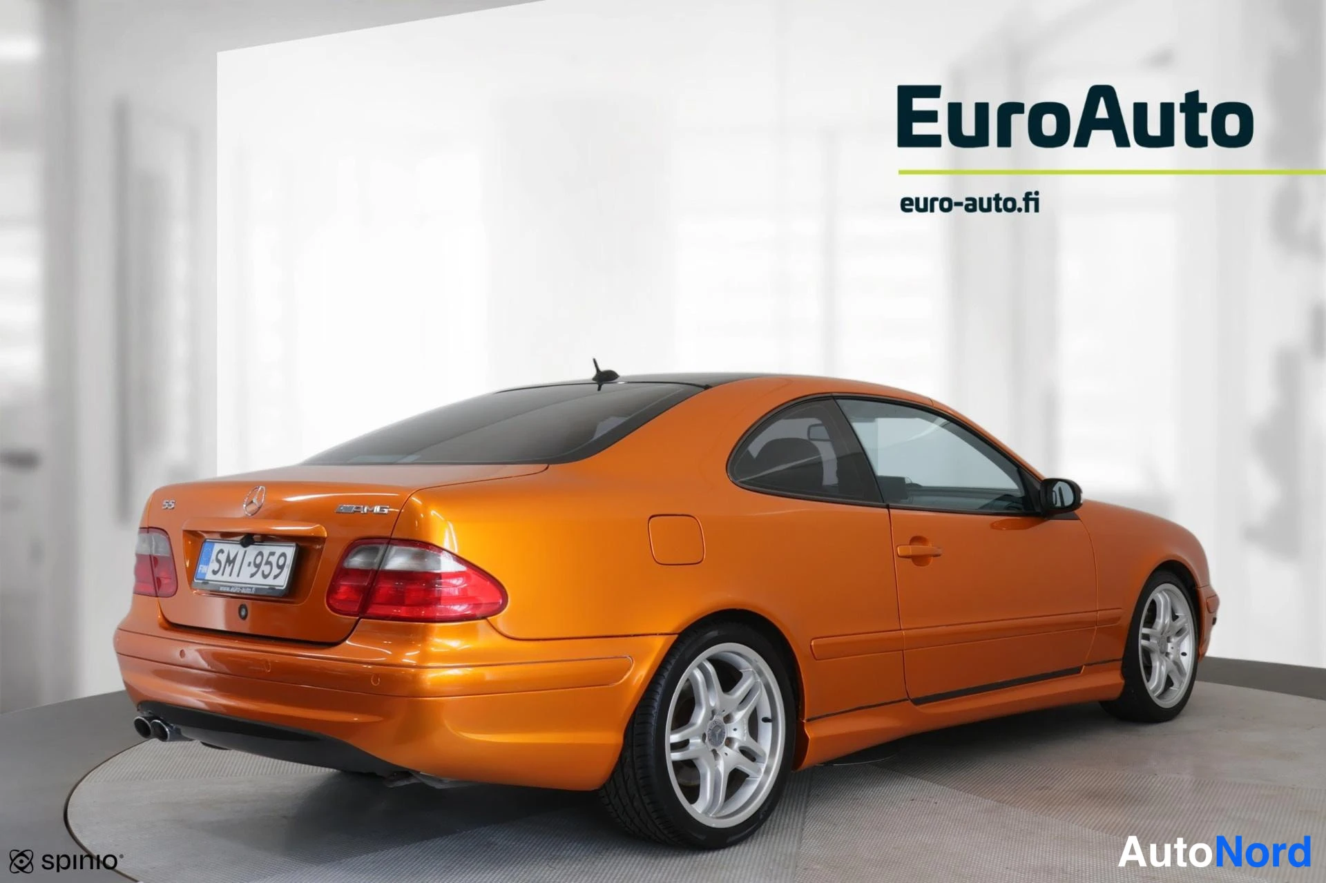 Takaviisto: Orange Mercedes coupe viewed from a rear three-quarter angle showing both the rear face and driver's flank, highlighting alloy wheels and roofline