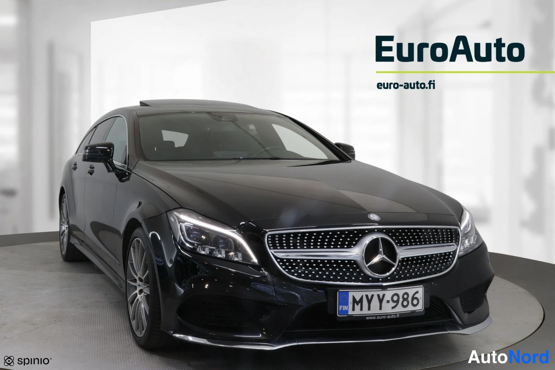 Etuviisto, nokka oikealle: Oikea kulma: musta Mercedes-Benz-asema. Etuosa ja vasen kylki näkyvillä. Valo päällä, rekisterinumero