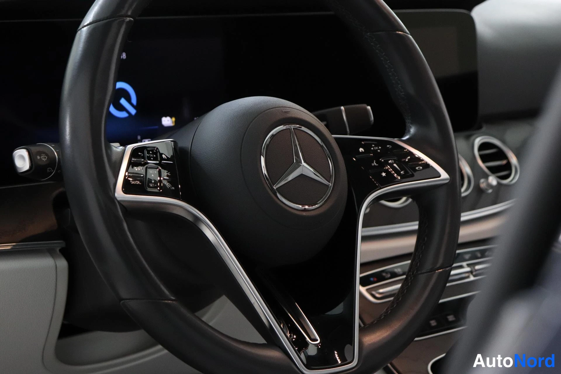 Sivulta: monitoimiohjauspyörä Mercedes-tähdellä, taustalla kojelaudan näyttö ja ilmastointisuuttimet.