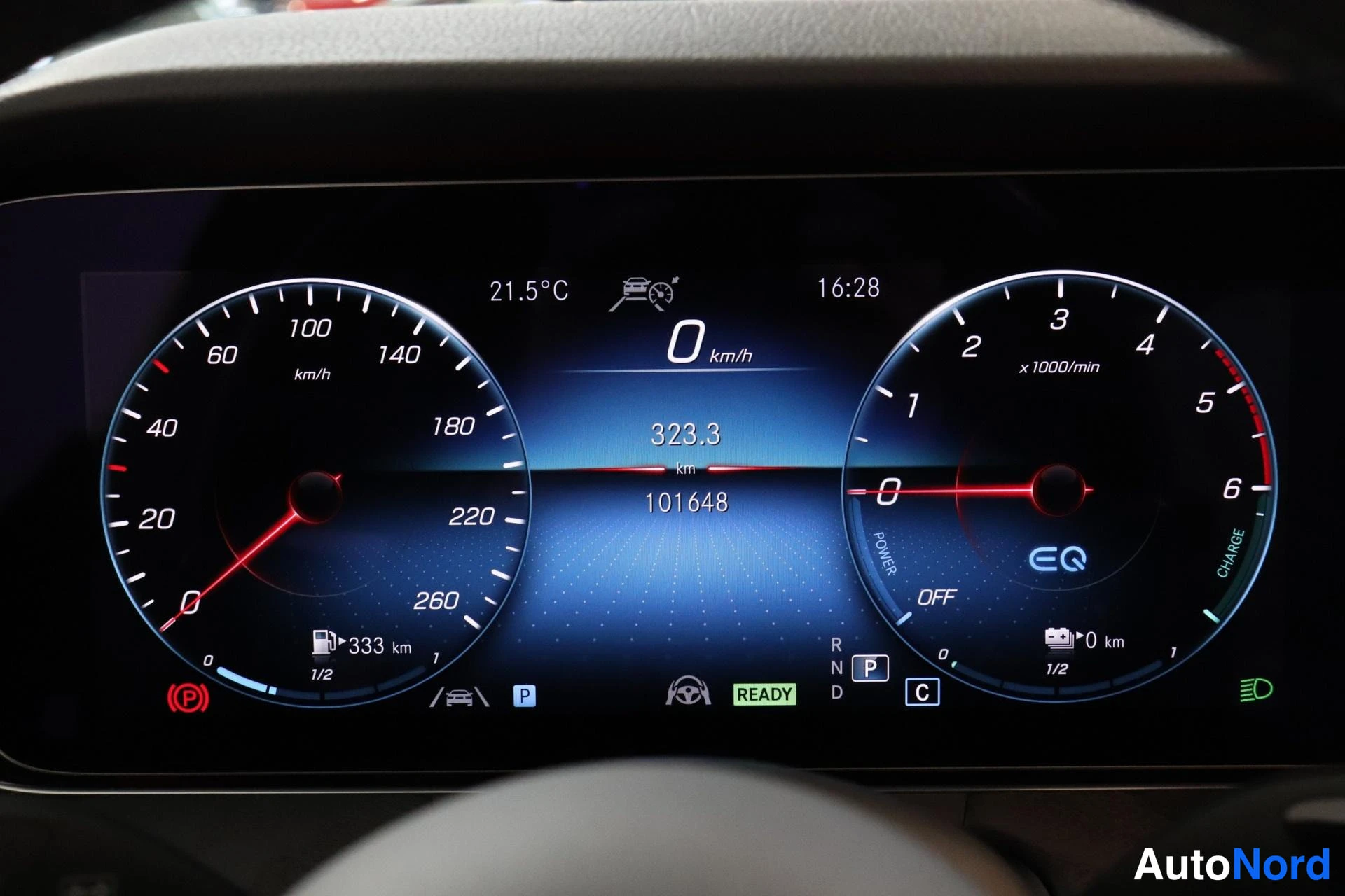 Yksityiskohta: Kojelaudan näyttö: nopeus 0 km/h, kokonaislukema 101 648 km, ulkolämpötila 21,5 °C ja READY-merkintä.