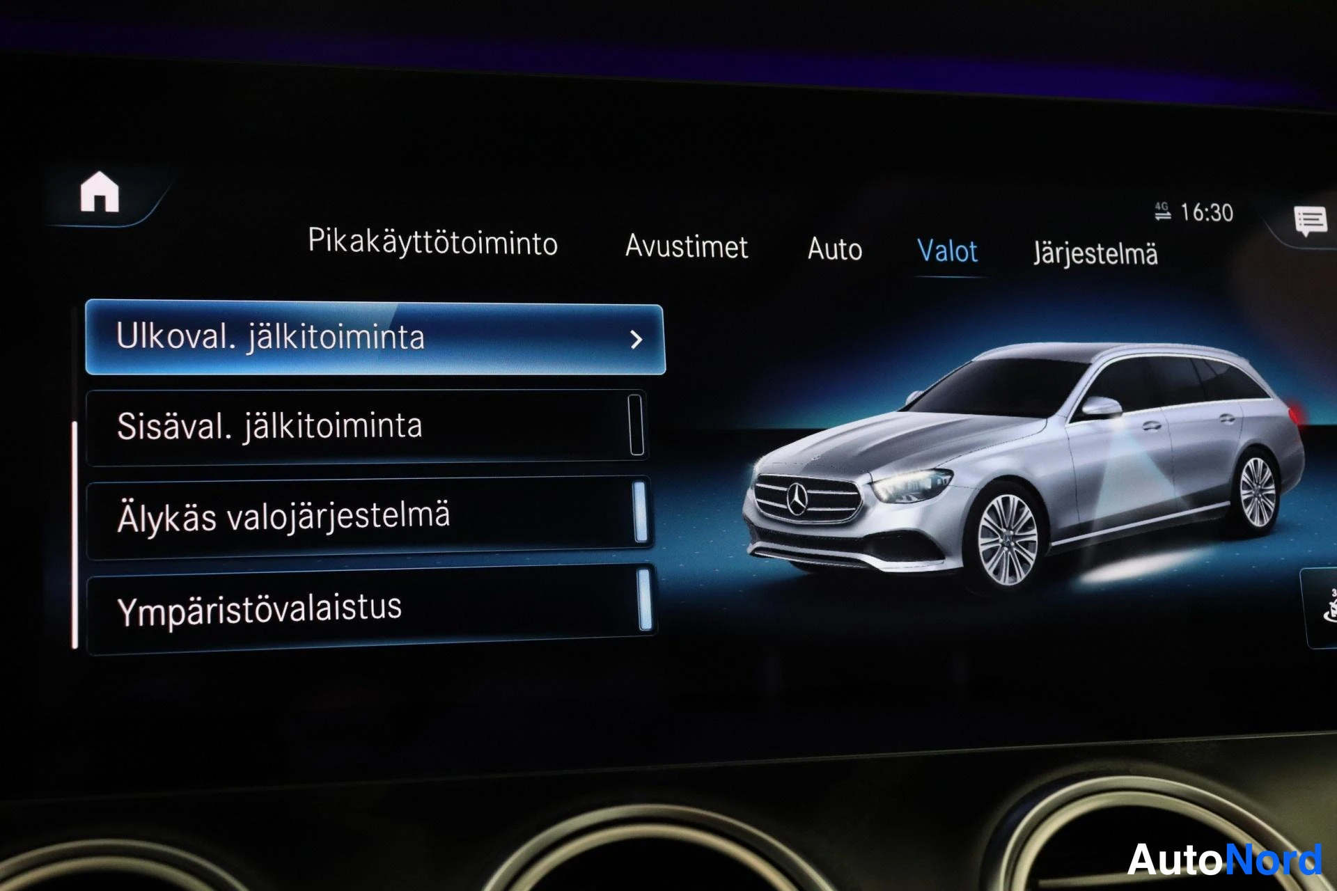 Muu: Keskusnäytön kuva, jossa näkyy 'Valot'-valikko. Valikon elementtejä ovat 'Ulkovaloja jälkitilanne', 'Sisävaloja jälkitilanne', 'Älykäs valojärjestelmä' ja 'Ympä