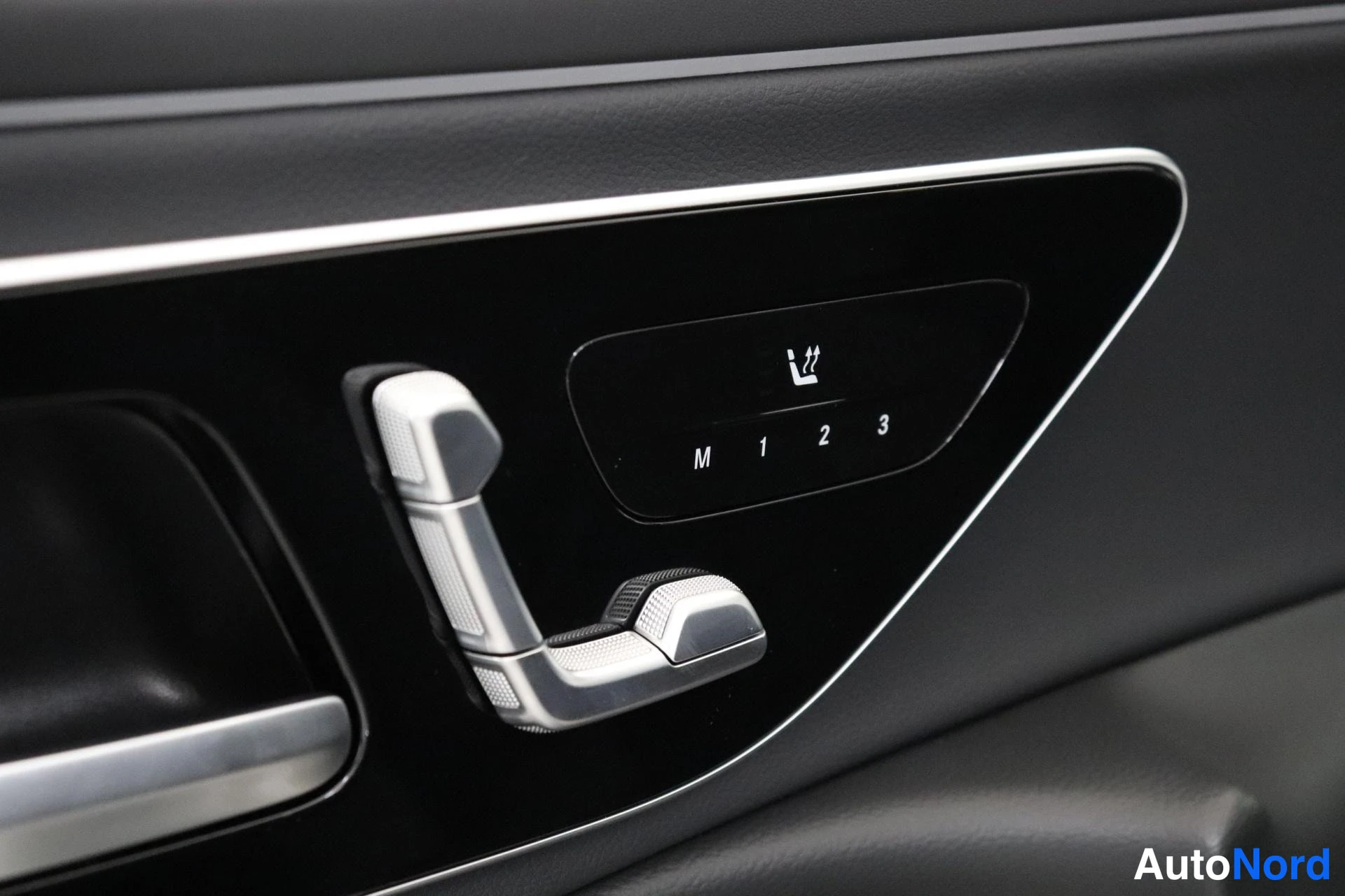Yksityiskohta: Close-up of the electric seat adjustment switch assembly on the inner door panel. A handle with integrated seatback angle controls is next to a memory button pa