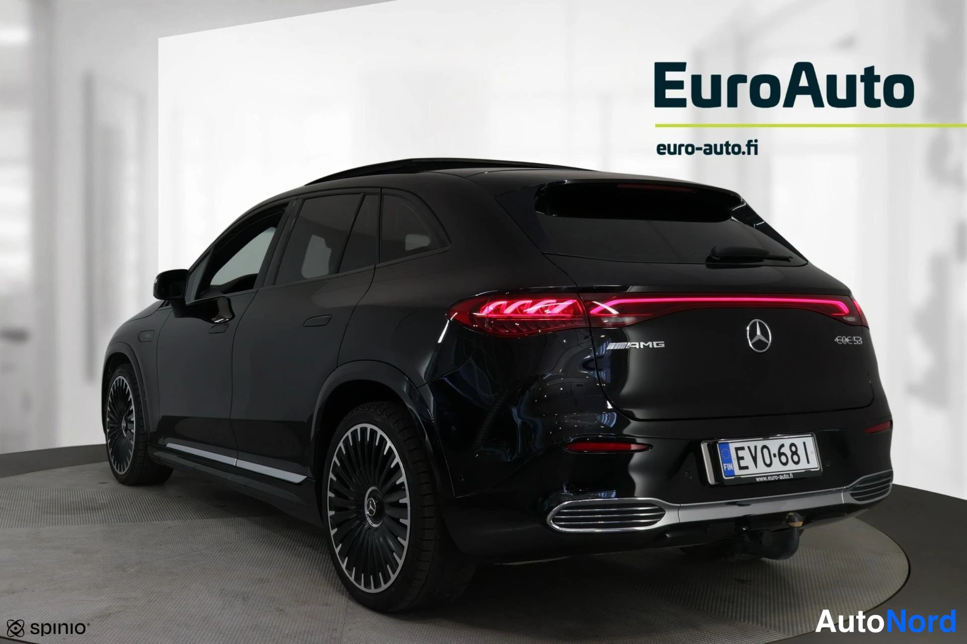 Takaviisto: Takakolmikulma kuva tummansinisestä Mercedes-Benz EQE 53 AMG SUV:sta. Takavaloilla on jatkuva LED-valojuova ja takana on vetokoukku. Kuvassa näkyvät myös AMG-pa