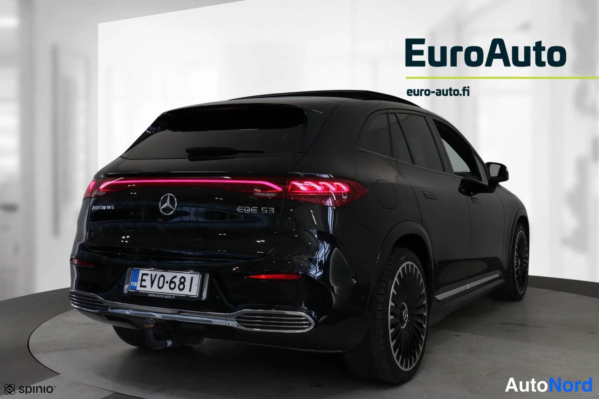 Takaviisto: Kuva mustasta Mercedes-Benz EQE 53 AMG SUV:sta kulmasta. Autossa on jatkuva LED-takavaloja ja vetoapupääty. Kuvassa näkyy myös AMG-merkki ja takavalot päällä. R