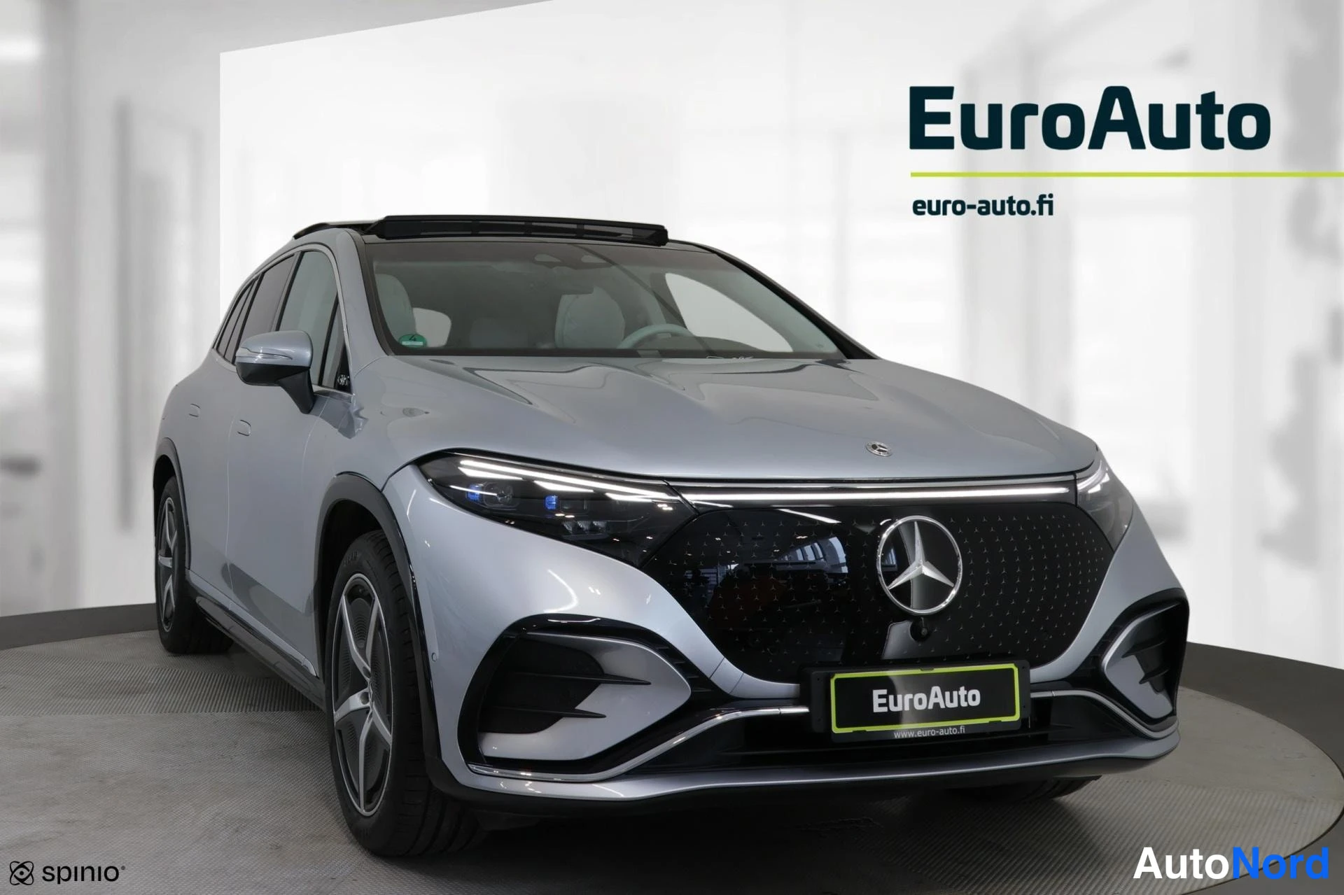 Etuviisto, nokka oikealle: Hopea Mercedes-Benz EQS lähes suoraan edestä kuvattuna; panoraamalasikatto ja kevytmetallivanteet näkyvät.