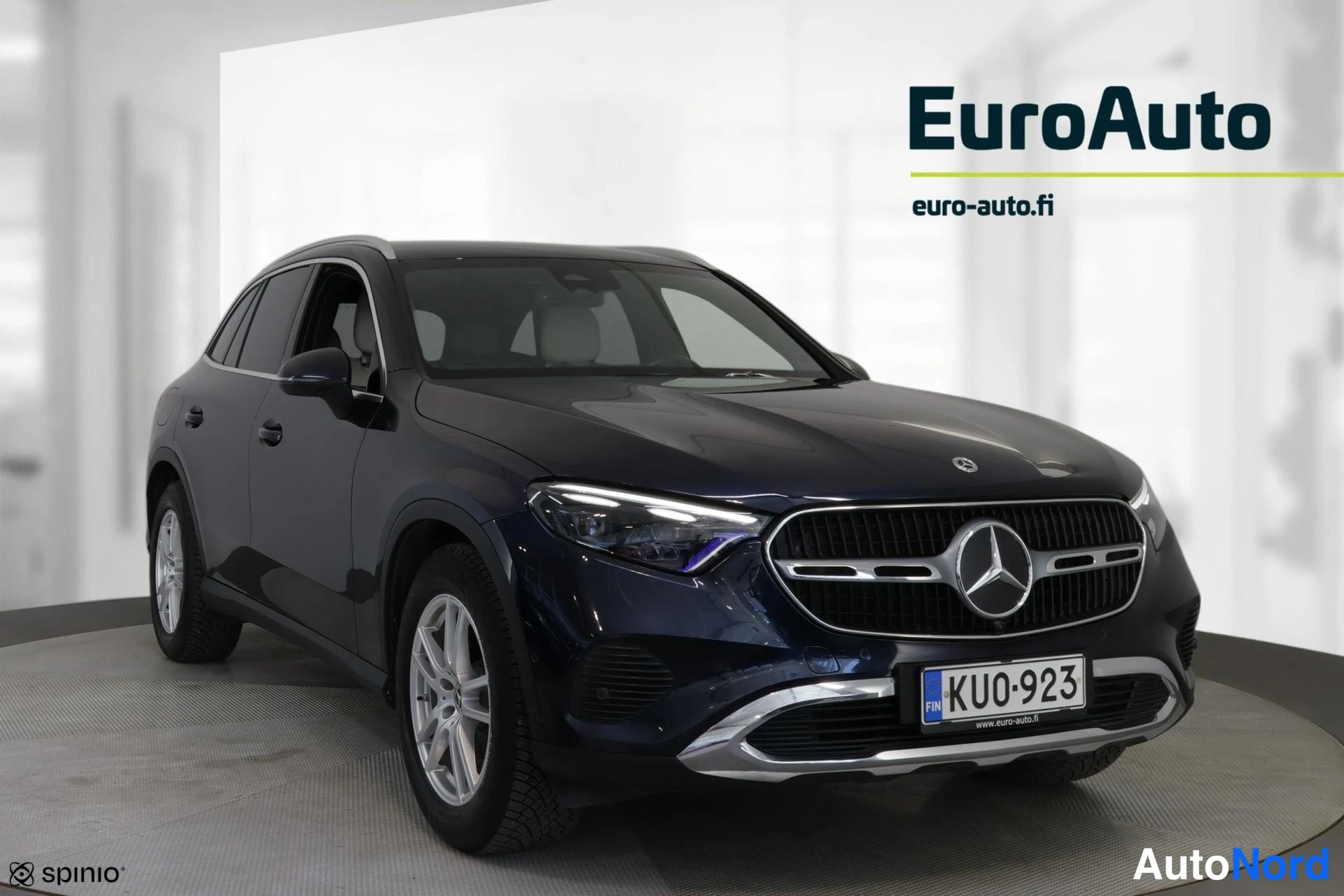 Etuviisto, nokka oikealle: Tummansininen Mercedes-Benz GLC etukulmasta, keula oikealla; etugrilli, ajovalot ja vasen kylki näkyvät valossa.