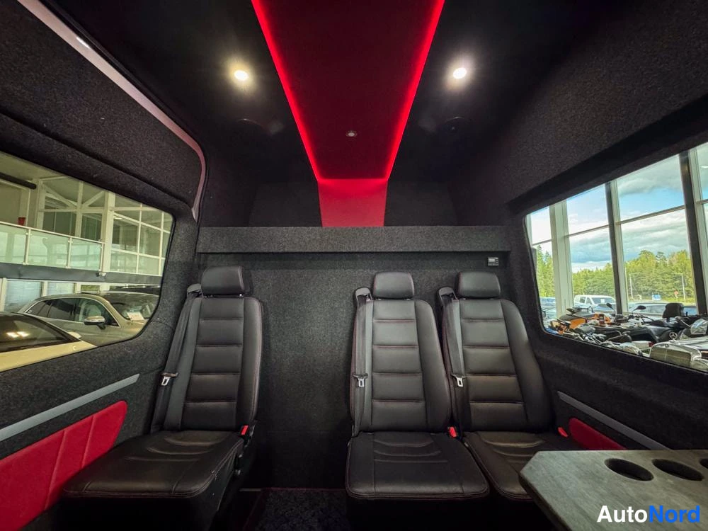 Takaistuimet: Interior shot from the rear of the cabin facing forward, displaying three individual black leather seats with red accent panels on the lower wall. Red LED strip