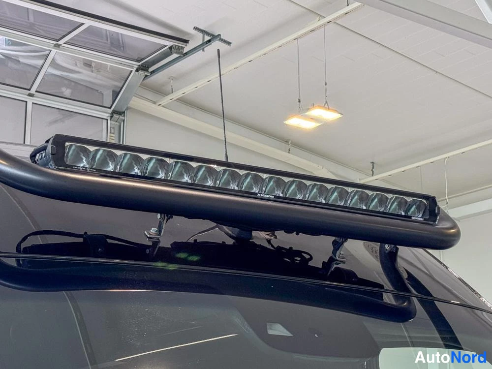 Yksityiskohta: Tæt billede af tagmonteret kørefogelyst (LED) i et garageinteriør. Lyset består af adskillige kugleformede LED-elementer placeret i række indenfor en sort besky