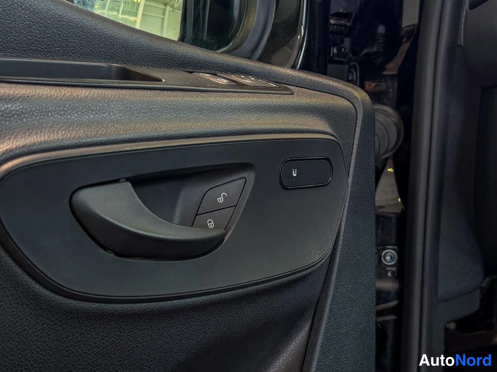 Ohjaamo: Tarkka kuva ohjausmoottorin ovipaneelista, jossa ovikahva, lukitusnappi ja sivulasin säätö.