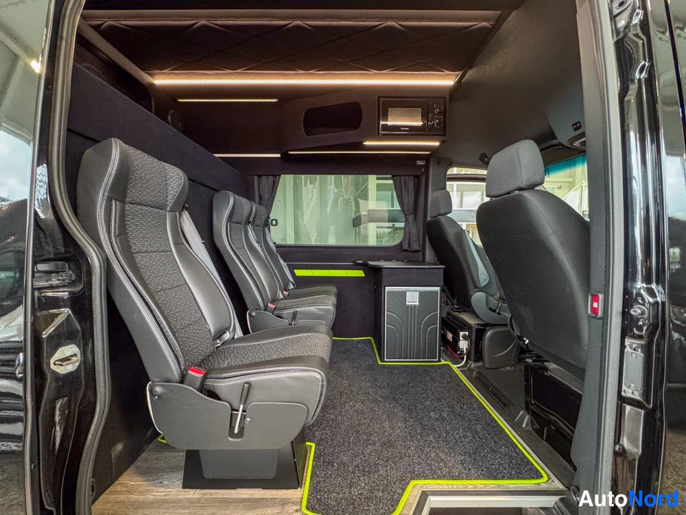 Ohjaamo: Interior of the cabin viewed from the open sliding door with three-row seating layout visible.