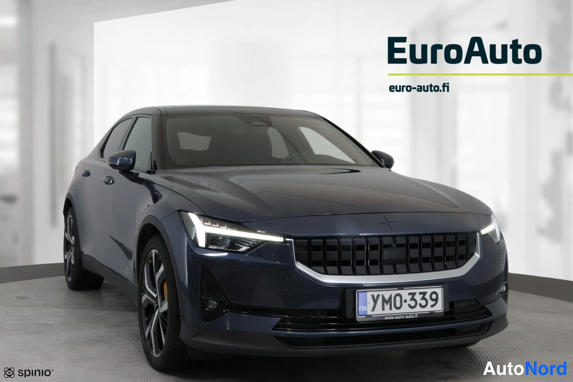 Etuviisto, nokka oikealle: Tummansininen sedan kuvattuna lähes suoraan edestä, kevyesti sivusta, keula oikealla; rekisterikilpi YM0-339, EuroAuto-logo taustalla.