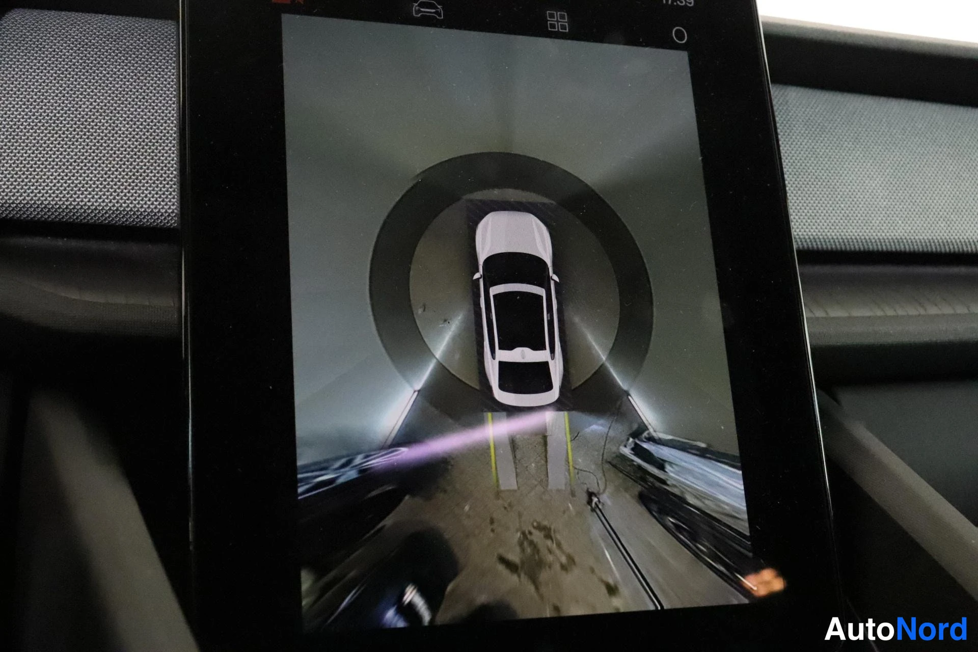 Yksityiskohta: Keskusnäyttö näyttää 360-kameran ylhäältä kuvatun näkymän autosta ja sen ympäristöstä.