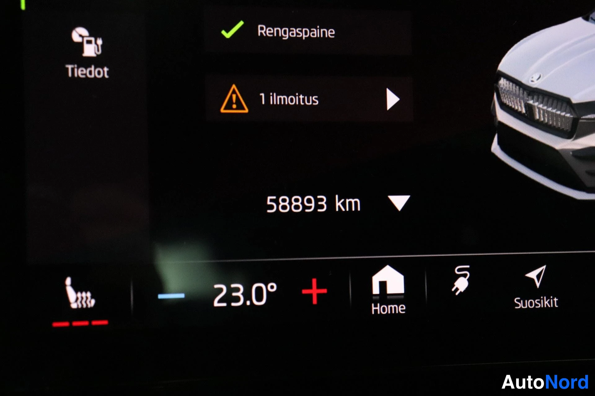 Muu: Auton infotainment-näyttö: matkamittari 58893 km, vihreä valintamerkki kohdassa Rengaspaine ja keltainen varoitusmerkintä '1 ilmoitus', lämpötila-asetus 23.0°.