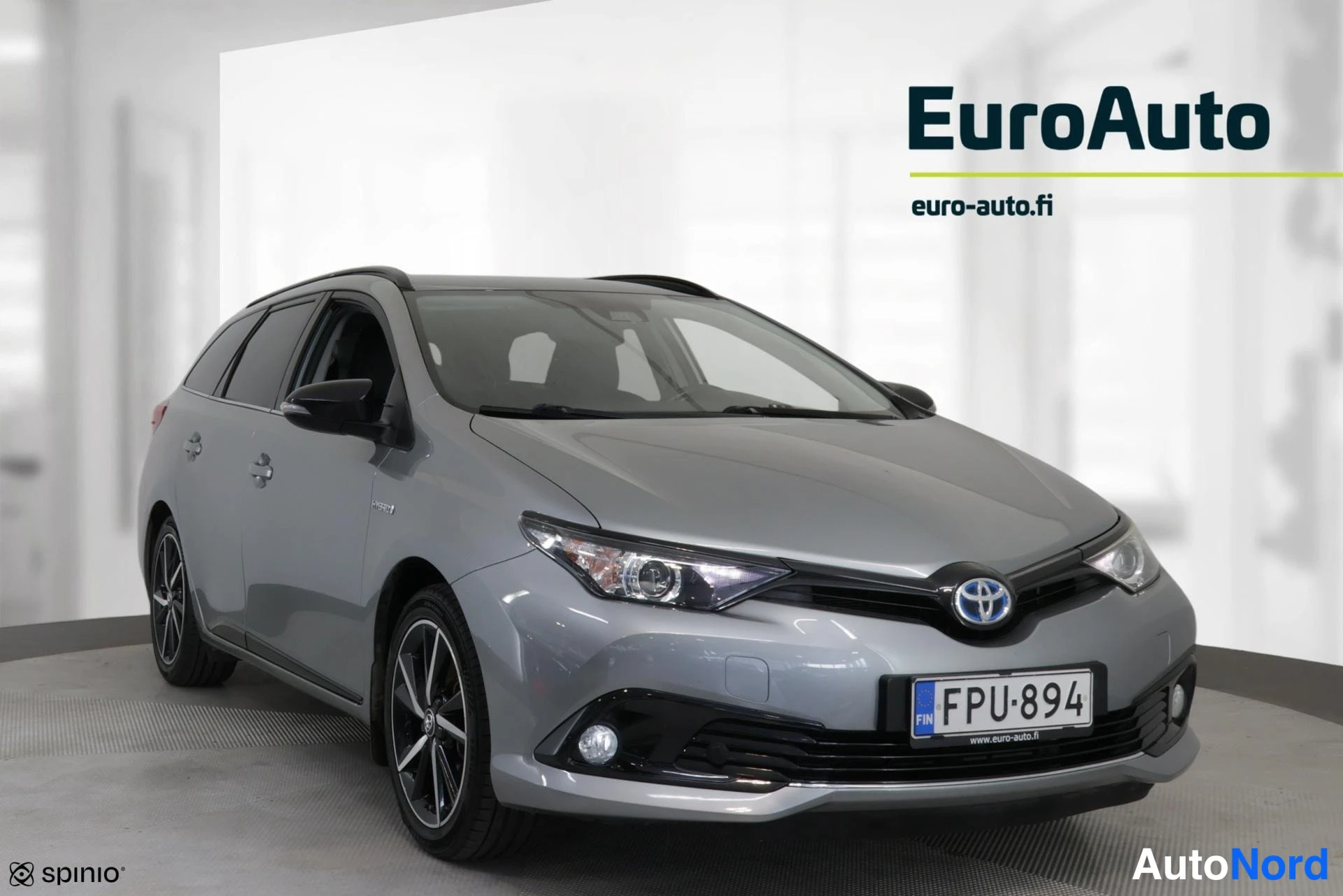 Etuviisto, nokka oikealle: Harmaa Toyota-farmari kolmeneljännäkuvassa keula oikealla, rekisteritunnus.