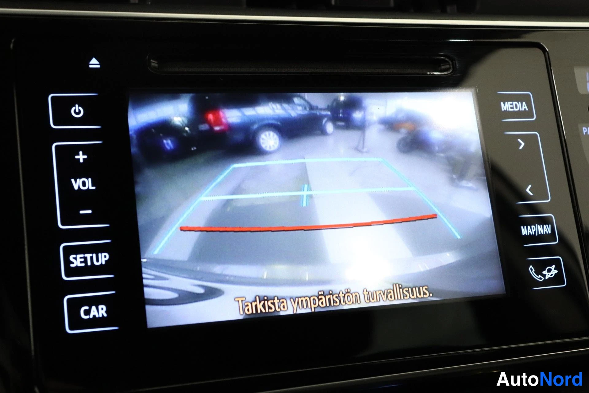 Ohjaamo: Rear view on the car's central infotainment screen. Parking guidelines are displayed, indicating the presence of a reversing camera.