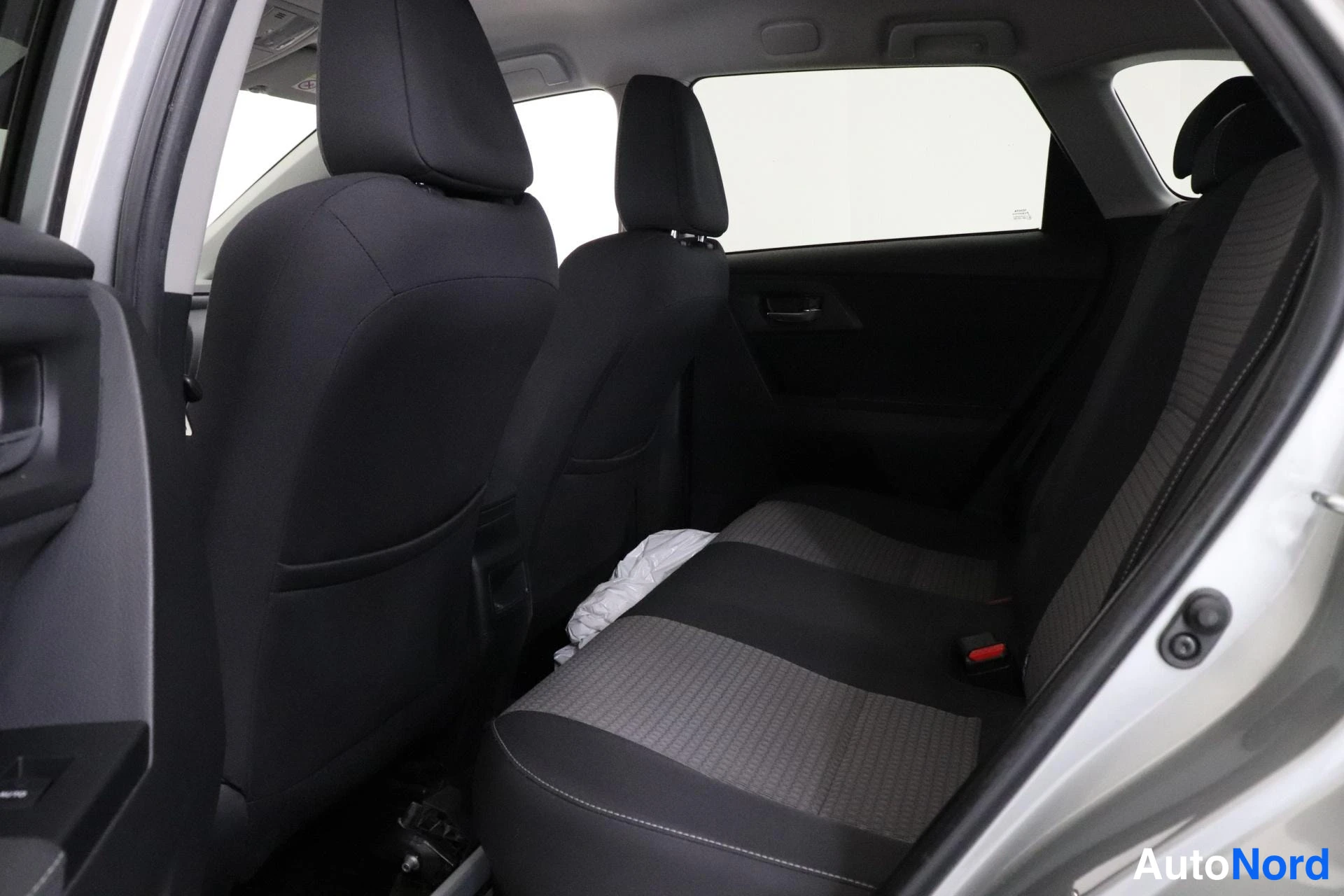 Takaistuimet: Rear passenger seats in a vehicle. Two headrests and seat belts are visible.