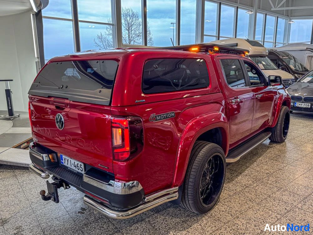 Takaviisto: Takaa oikealta otettu kuva. Punainen Volkswagen Amarok, jossa takaluukun yläpuolella kattonuppi. Takapalkissa vetoaita, ja vasemmassa takanurkassa '4MOTION'-tek