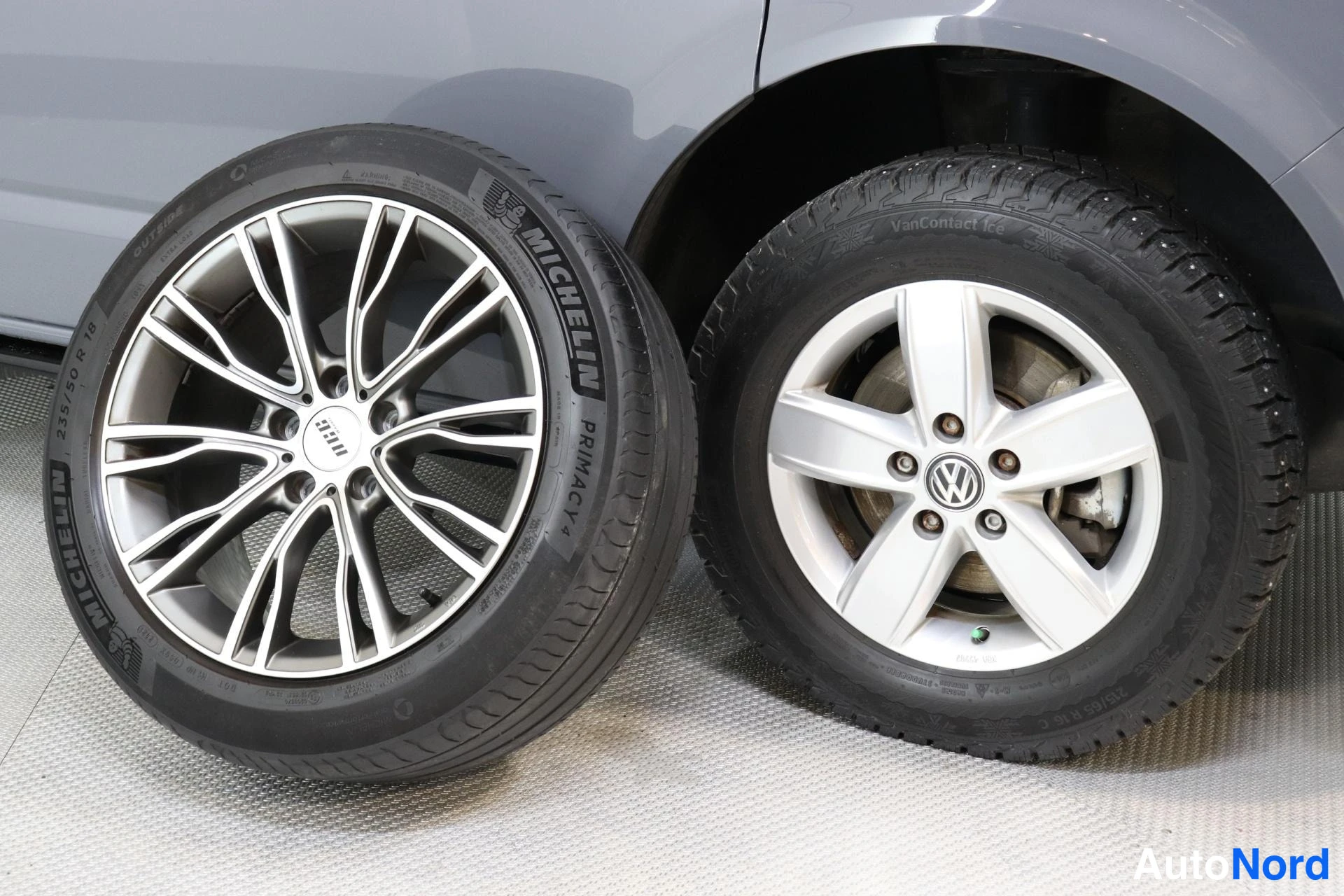 Muu: Kaksi alumiinivannetta vierekkäin: vasemmalla Michelin Primacy 4 -kesärengas vieraalla vanteella, oikealla autossa kiinni oleva Volkswagen-merkitty vanne Contin