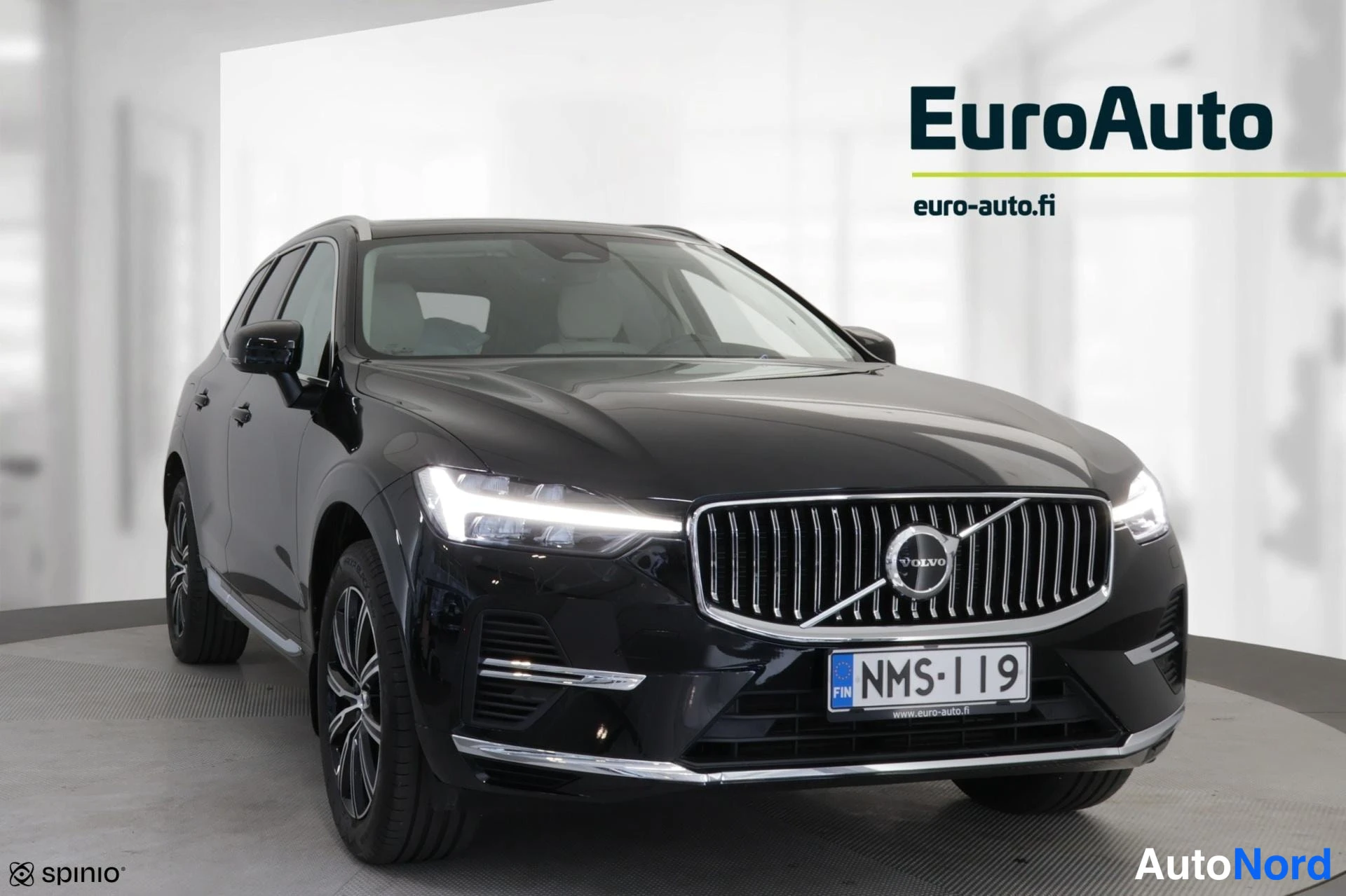 Edestä: Suora etukuva mustasta VolvoXC60:sta. Oikealta ja vasemmalta valaisevat LED-tunnelajut. Eturinnassa on Volvo-logo. Etupuskurissa on suuri grille ja alempana chr