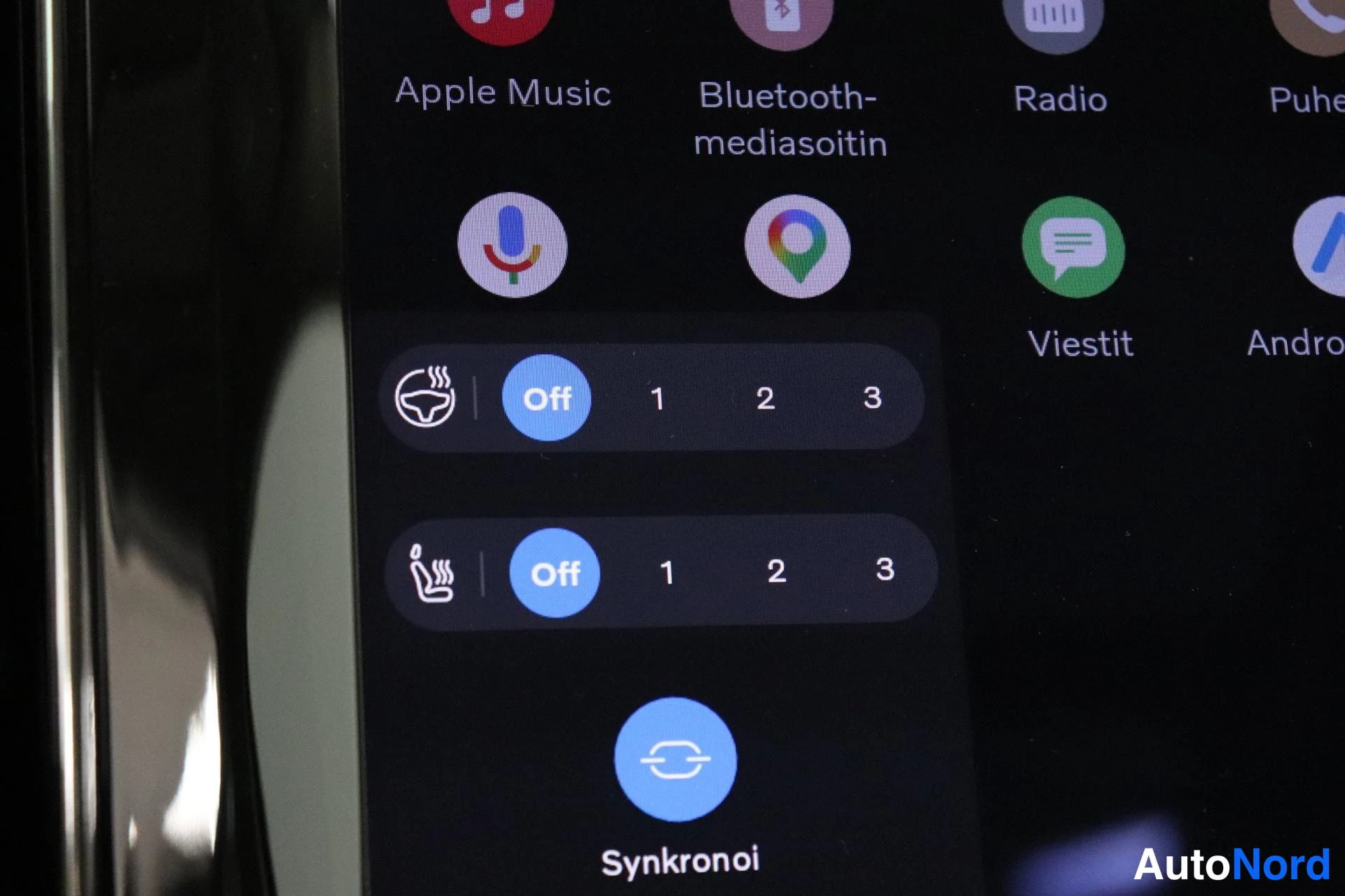 Ohjaamo: Kosketusnäytön lähikuva jossa on sovellusvalikko. Näkyvillä ikonit: Apple Music, Bluetooth-mediastoittimen nimi, Radio, Puheohjaus, Viestit, Android Auto. Alhaa