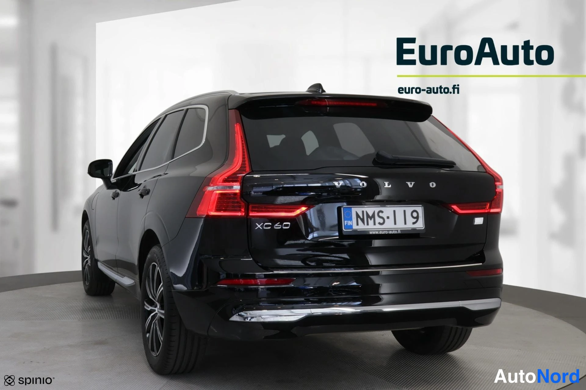 Takaviisto: Mustan Volvo XC60:n takakulmanäkymä; takaluukussa VOLVO- ja XC60-tekstit, rekisterikilpi, punaiset takavalot, kattosporaani ja takapyhinä itseVakkarakyhä itse.