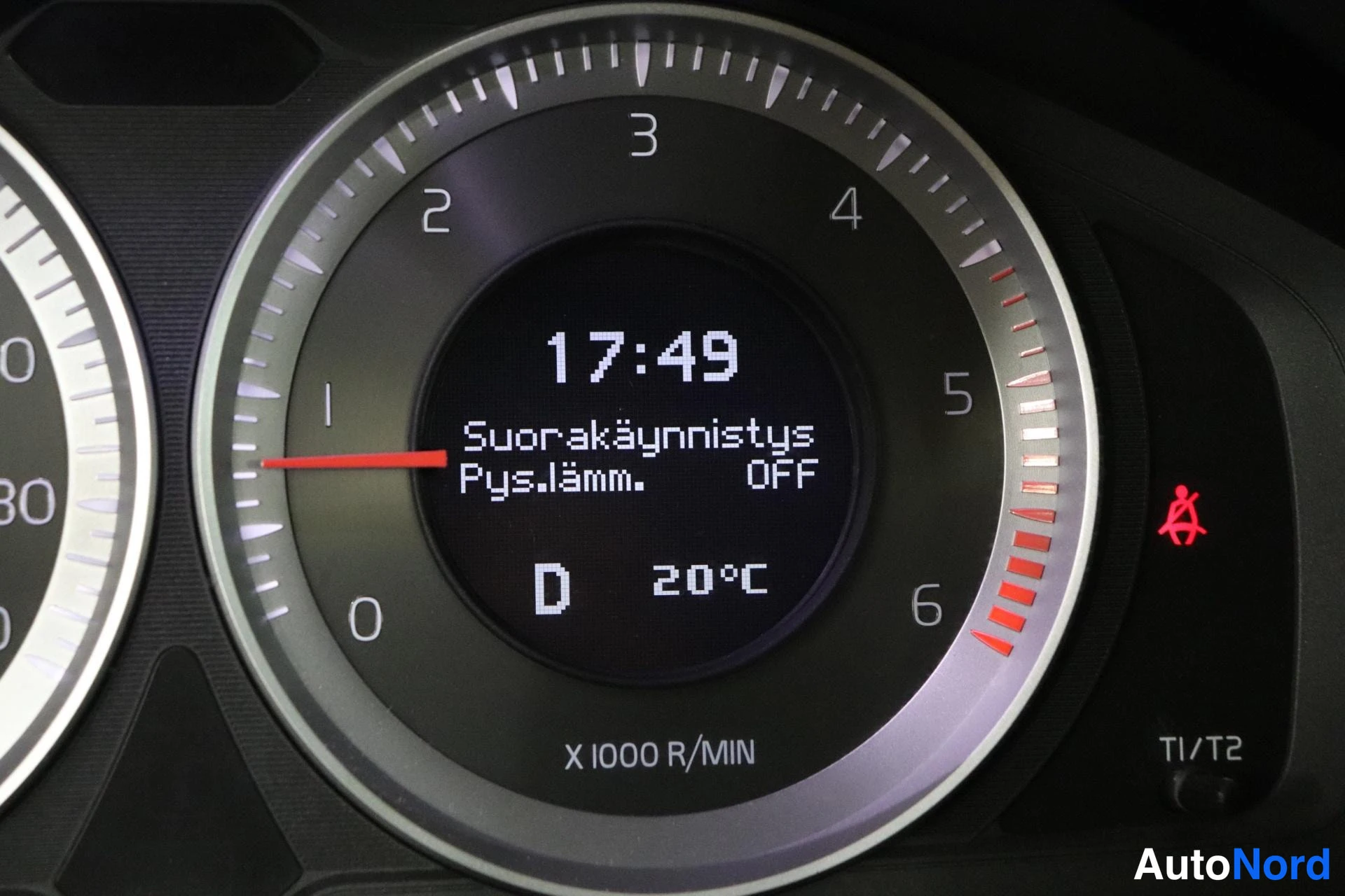 Ohjaamo: Oikea puoli mittaristosta. Keskellä on digitalinen näyttö kellon 17:49, vaihdevalitsin D (Drive) ja ulkolämpötila 20°C. Ruudun yläosassa teksti 'Suorakäynnistys