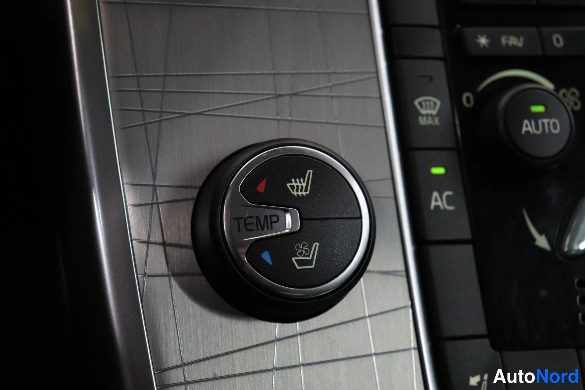 Yksityiskohta: Close-up of the climate control panel showing a temperature dial and buttons labeled 'AC', 'AUTO', and fan speed.
